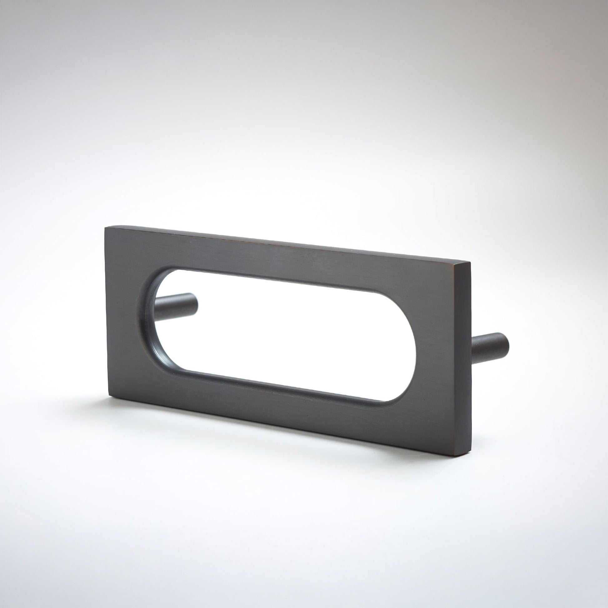 A matte black rectangular drawer pull with an elongated oval cutout, shown on a clean light gray 