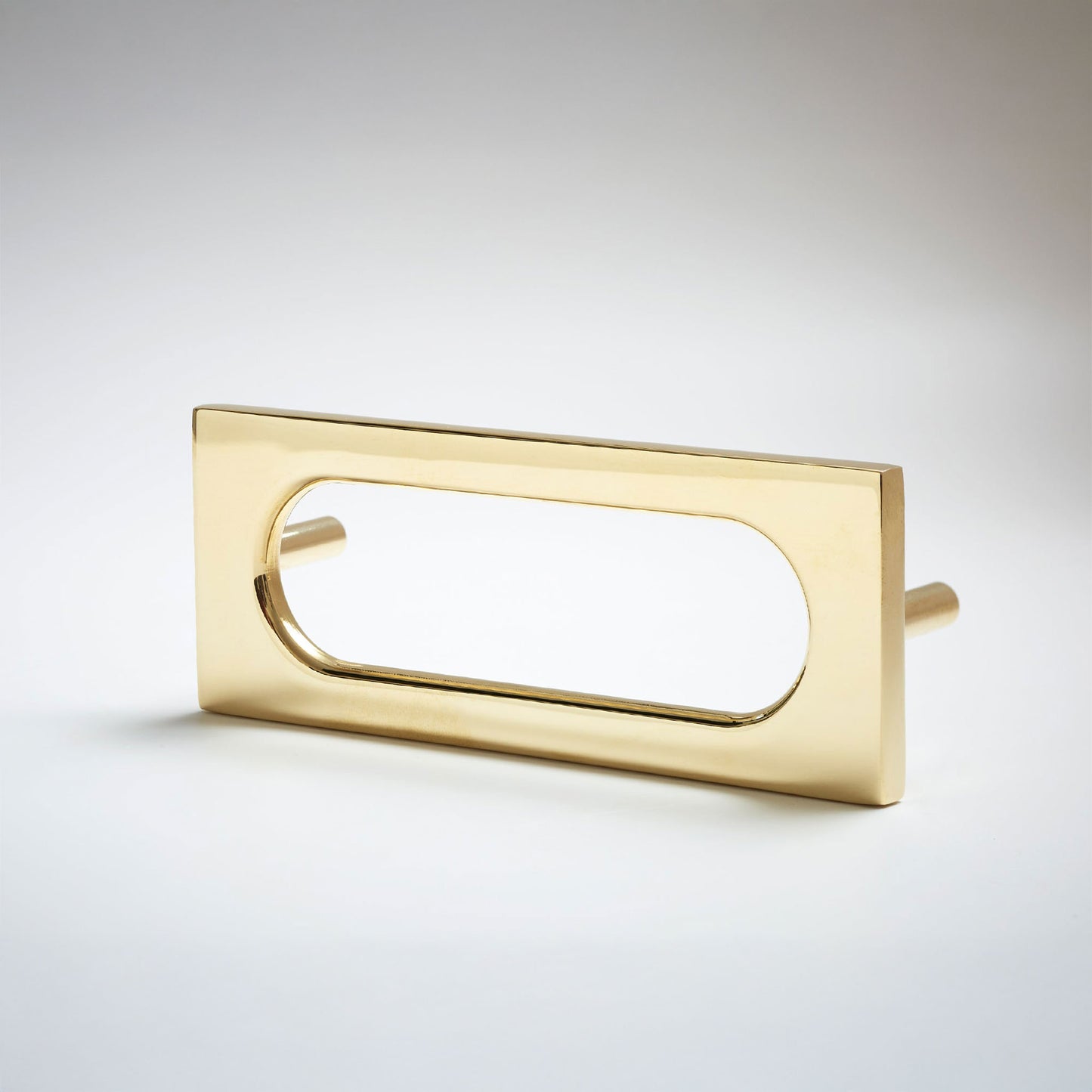 A polished brass rectangular drawer pull with an elongated oval cutout, shown on a clean light gray background.