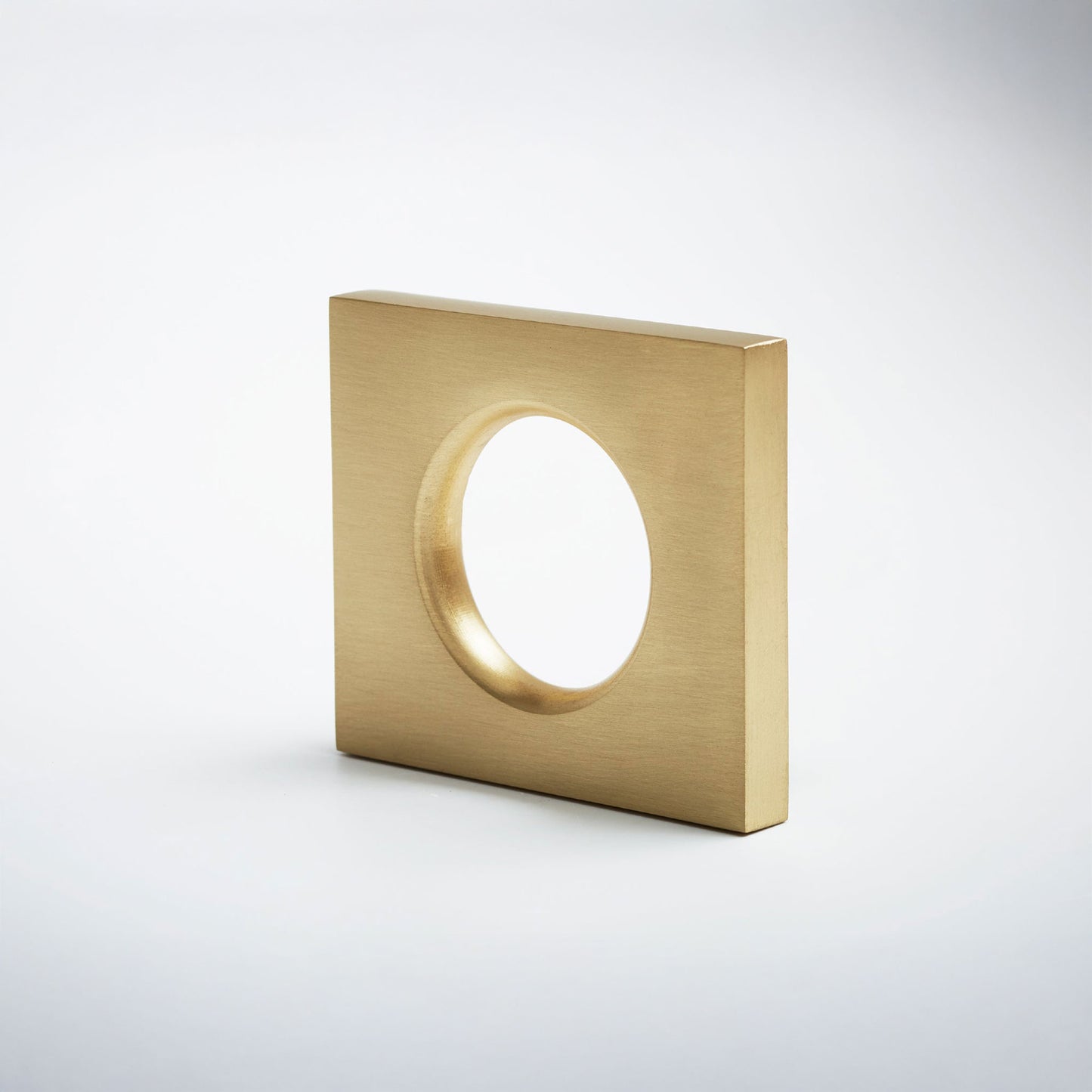 A modern square metal cabinet pull with a circular cutout in the center, shown on a clean light gray background.