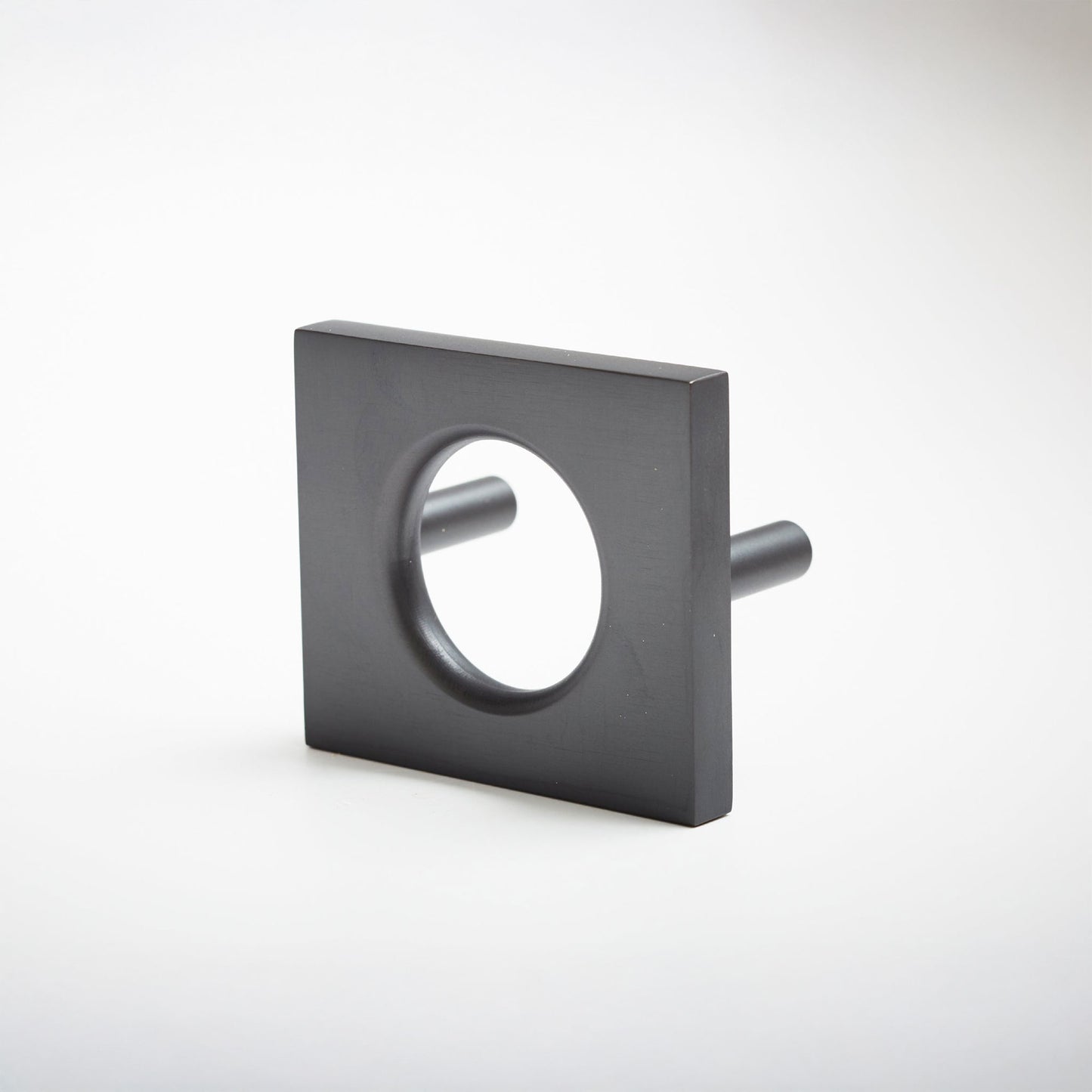 A modern square metal cabinet pull with a circular cutout in the center, shown on a clean light gray background.