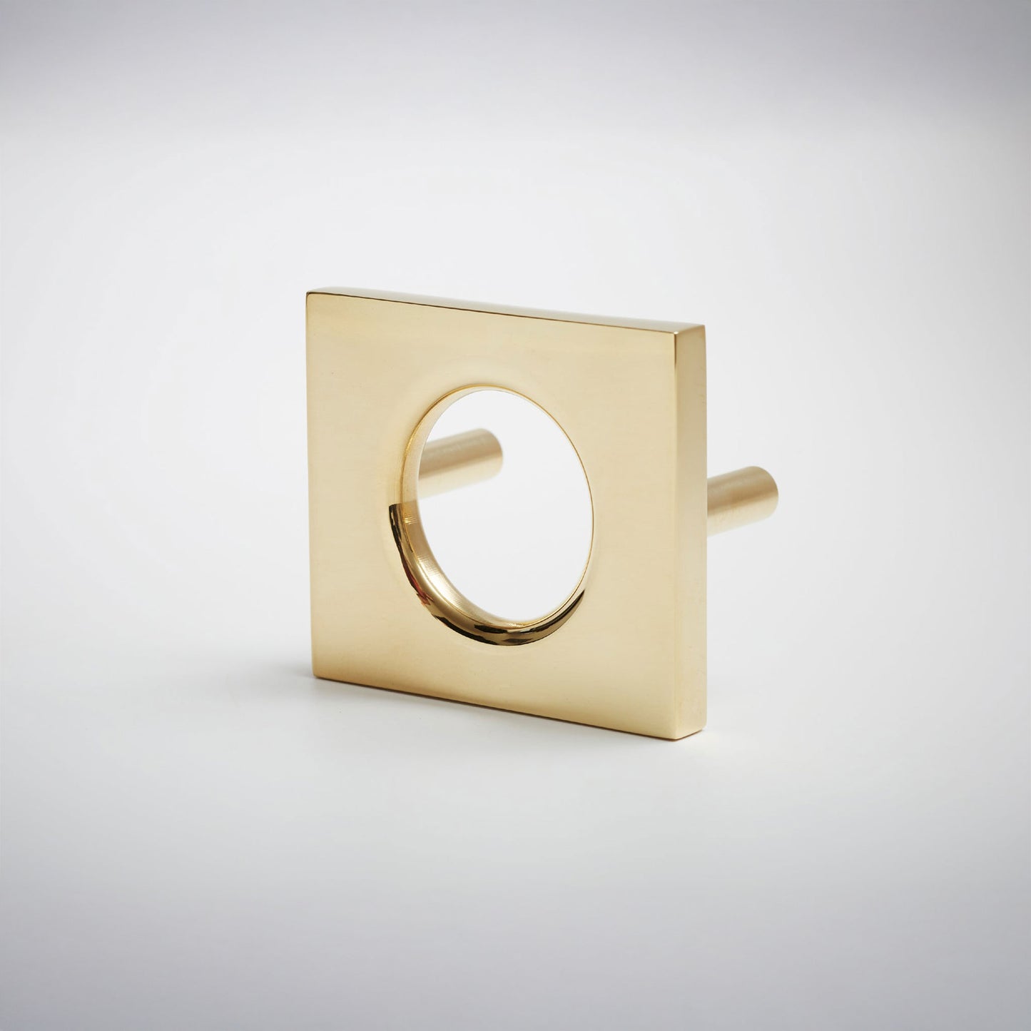 A modern square metal cabinet pull with a circular cutout in the center, shown on a clean light gray background.