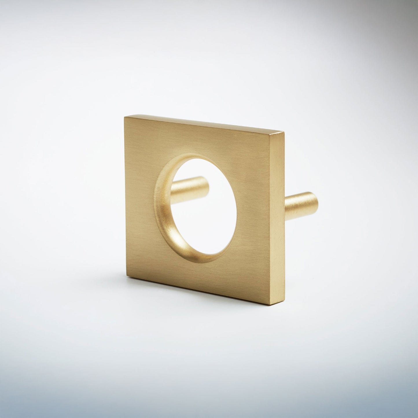 A modern square metal cabinet pull with a circular cutout in the center, shown on a clean light gray background.