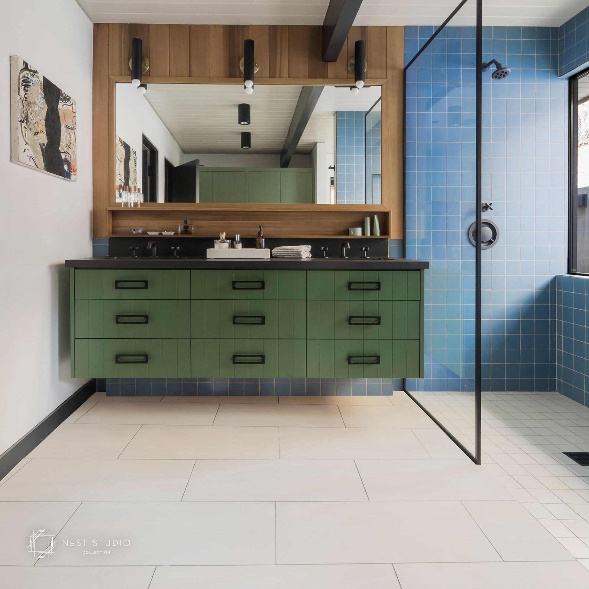 A modern floating double-sink bathroom vanity in sage green, mounted beneath a large wood-framed mirror. The vanity has black countertops and black hardware.