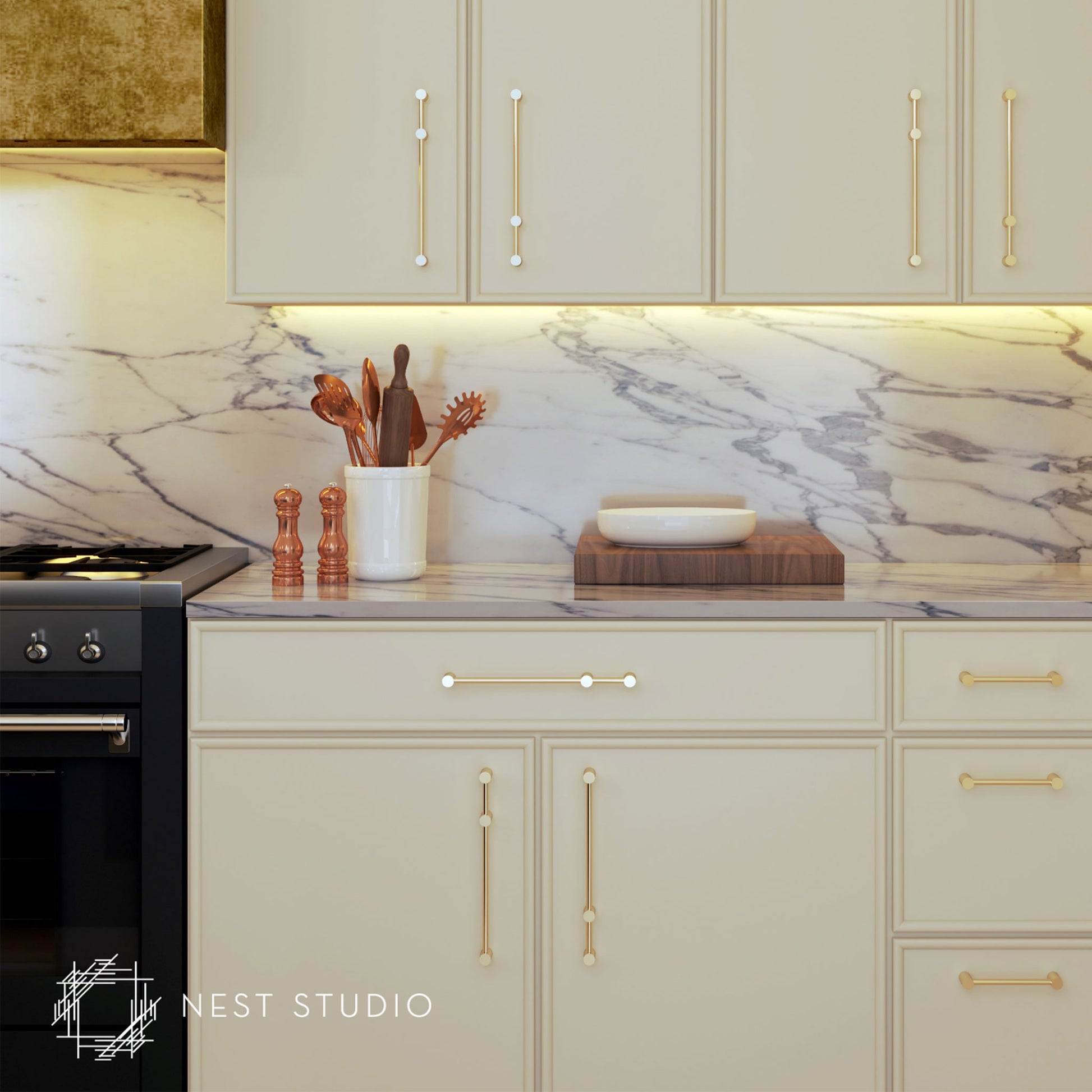 Cream-colored kitchen cabinets with elegant gold and brass bar handles, set against a white marble backsplash. A white ceramic utensil holder, copper-toned salt and pepper shakers, and a wooden cutting board are arranged on the marble countertop.