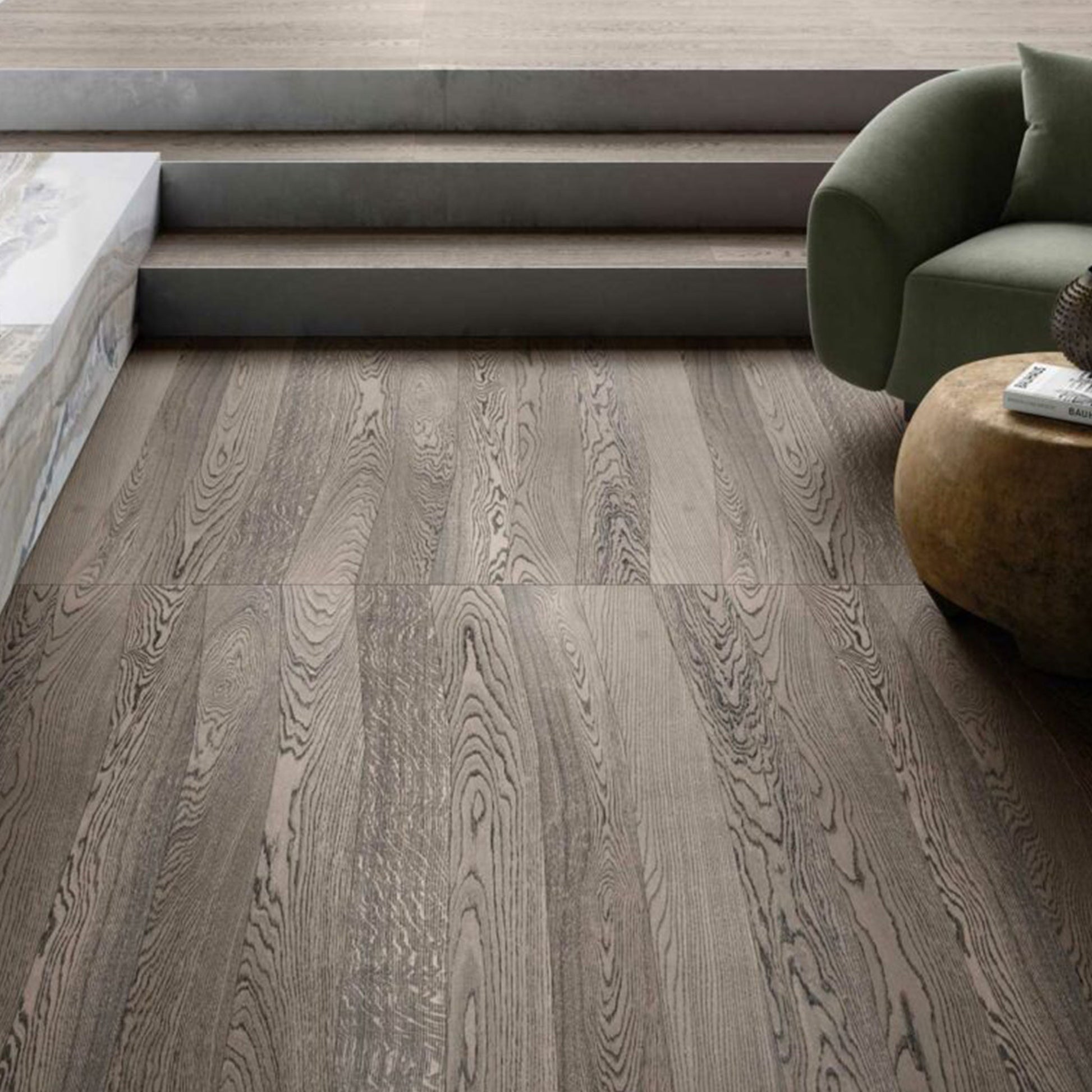 Wooden flooring with a modern interior setting featuring a green sofa and a round ottoman.