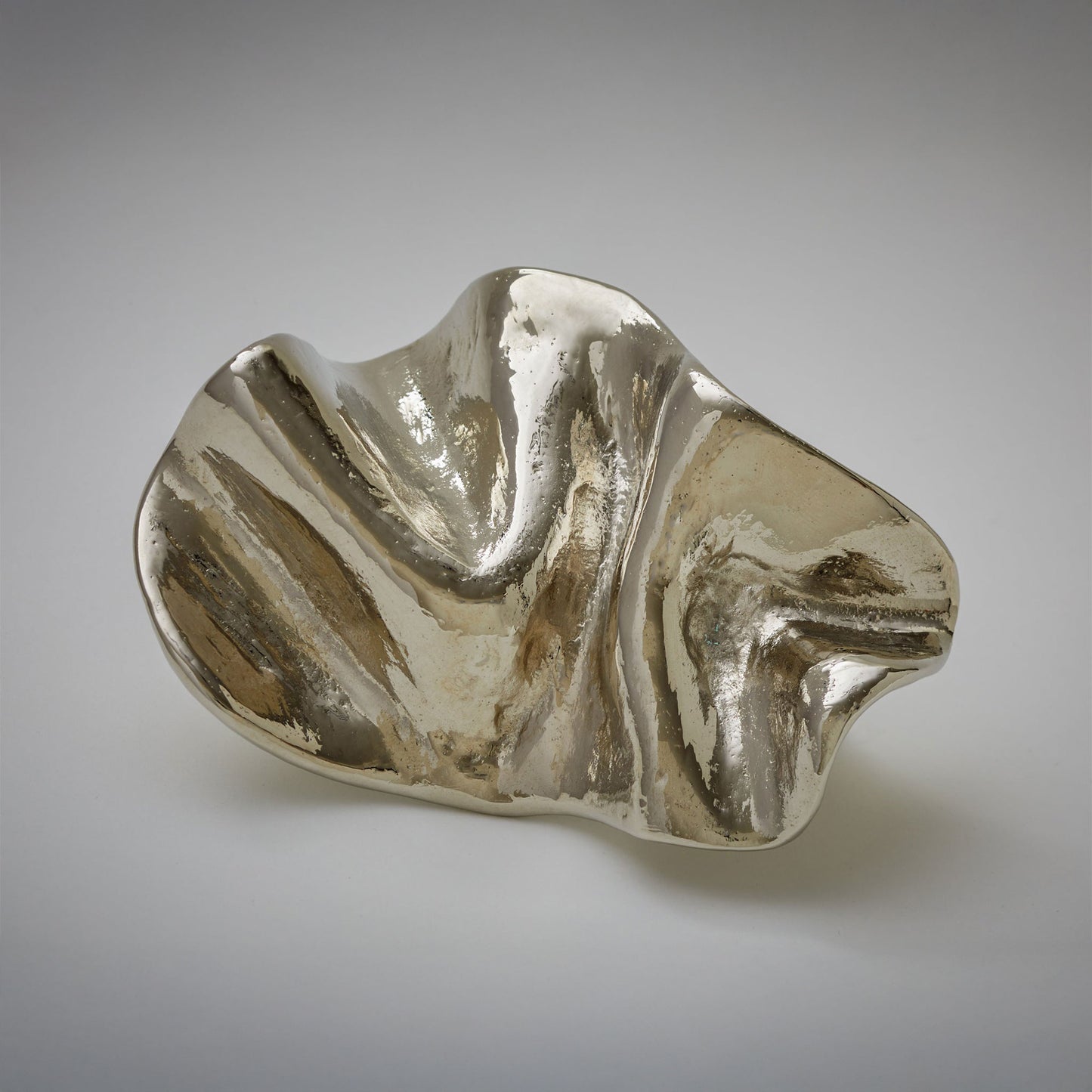 An organic-shaped cabinet pull with a glossy, wavy surface, photographed on a neutral light gray background.