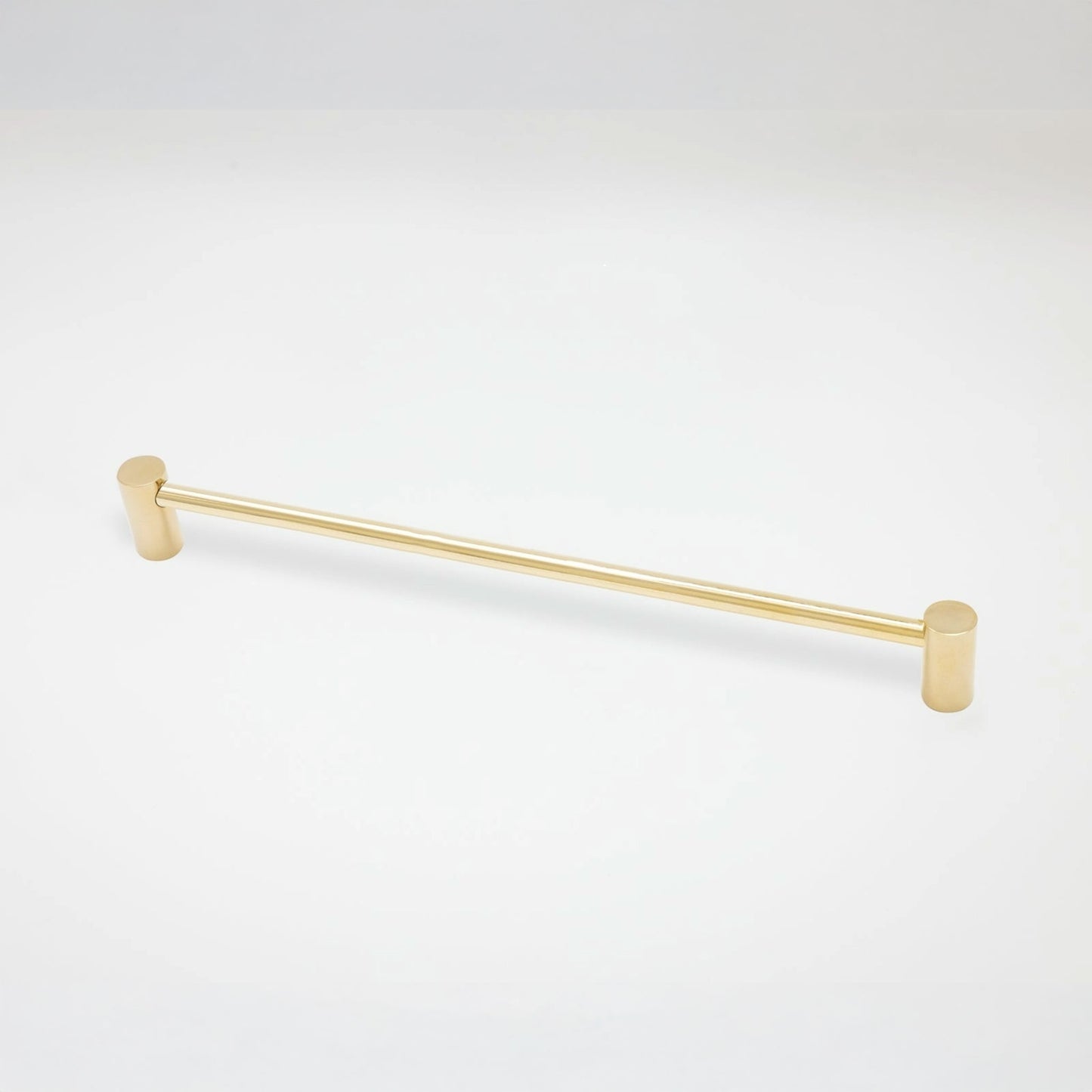 A modern cabinet pull with a brushed gold finish, featuring cylindrical end caps, shown against a plain white background.