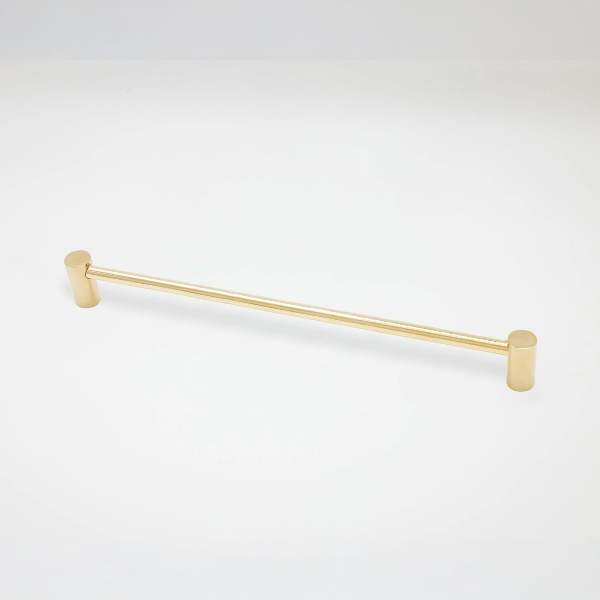 A modern cabinet pull with a brushed gold finish, featuring cylindrical end caps, shown against a plain white background.