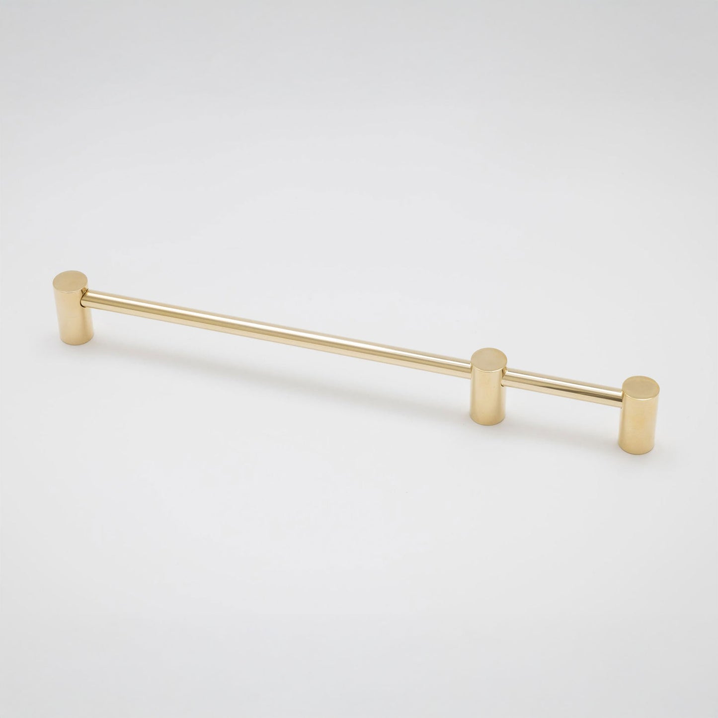 A modern horizontal cabinet pull handle with a brushed gold finish, featuring cylindrical end caps and a slim central bar, shown on a light gray background.