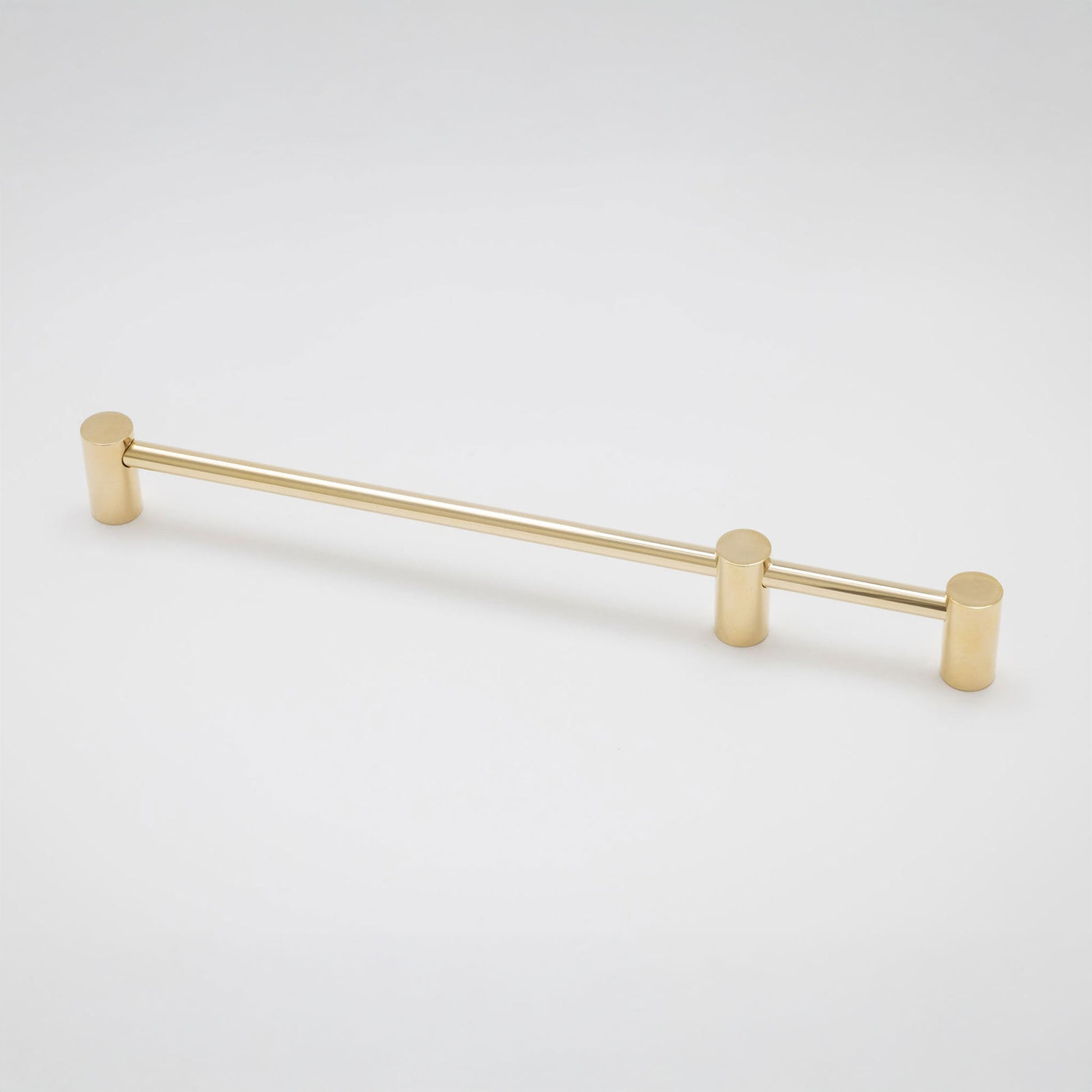 A modern horizontal cabinet pull handle with a brushed gold finish, featuring cylindrical end caps and a slim central bar, shown on a light gray background.