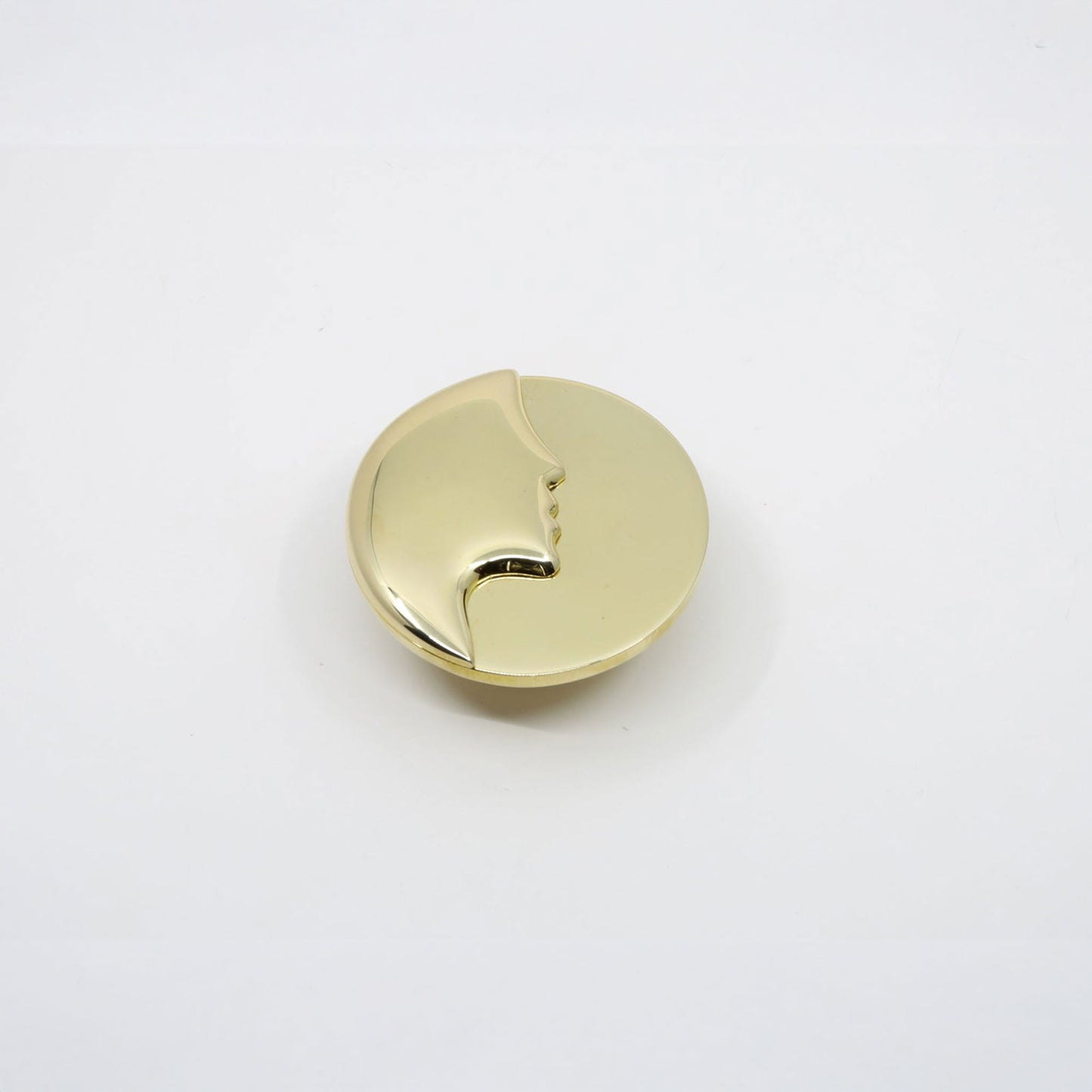 A single round, polished gold cabinet knob with a small cutout detail, shown on a plain white background.
