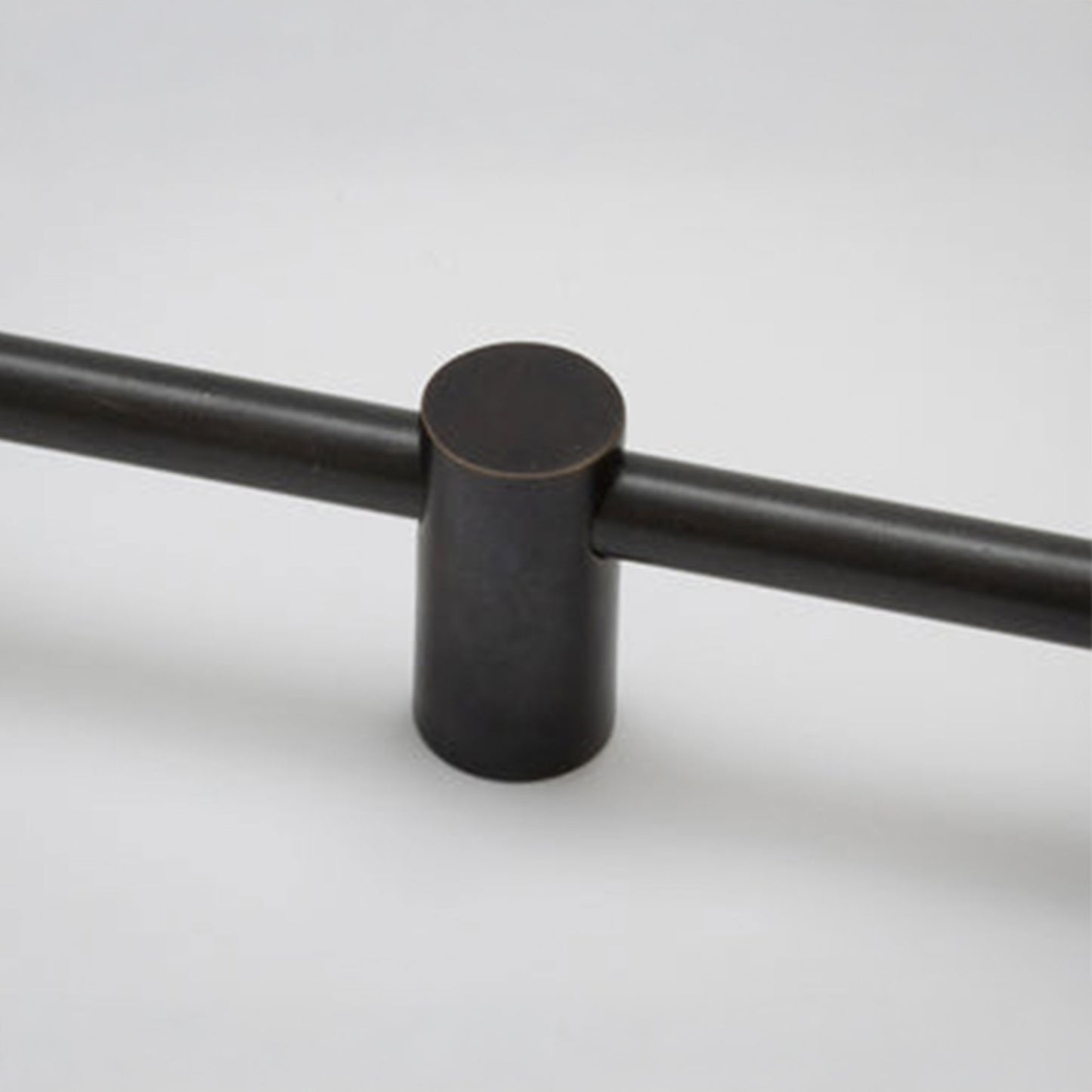 A close-up of a matte black cylindrical cabinet knob with a horizontal bar extending to both sides, set against a light gray background.
