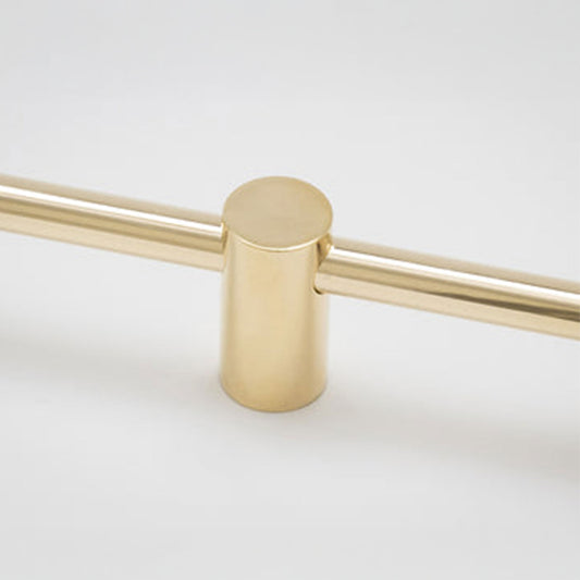 A close-up of a brushed brass or gold-finished metal hardware piece, showing a cylindrical post connected to two horizontal bars on a plain light background.