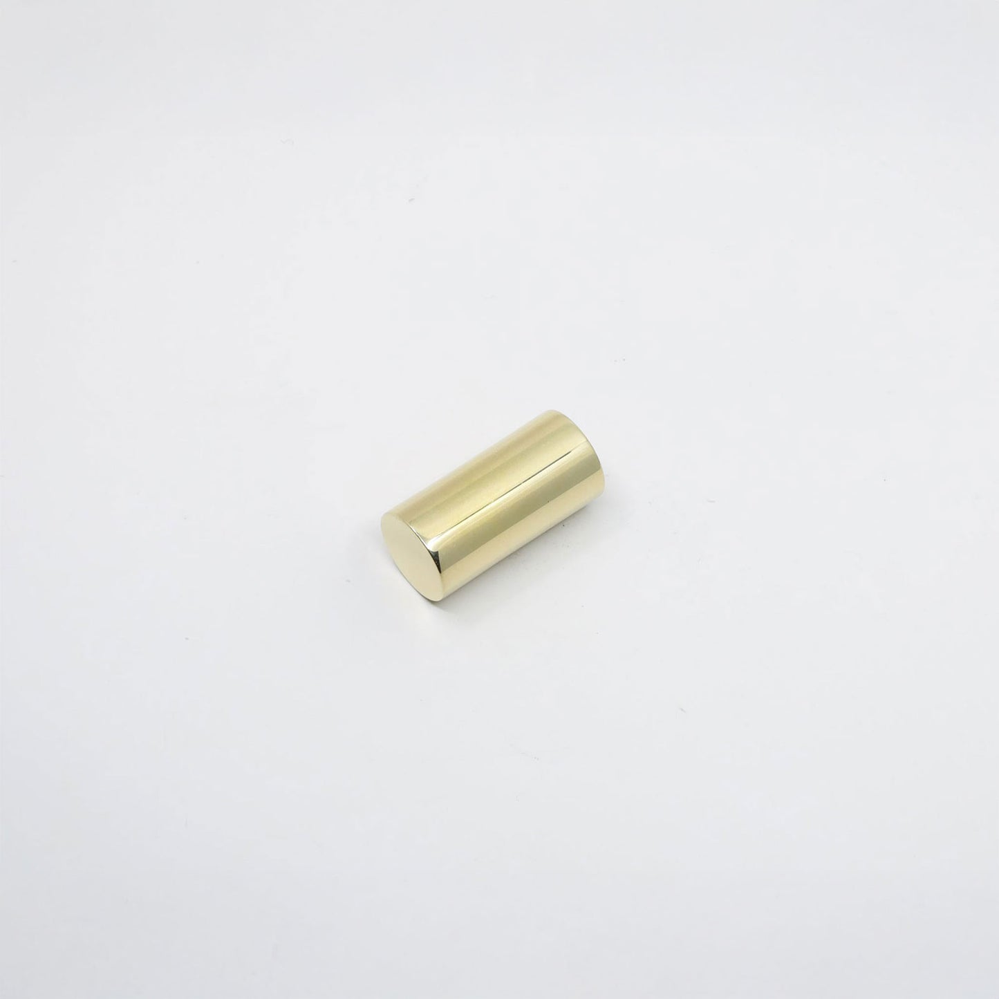 A small cylindrical metallic knob with a brushed gold finish, photographed on a seamless white background.