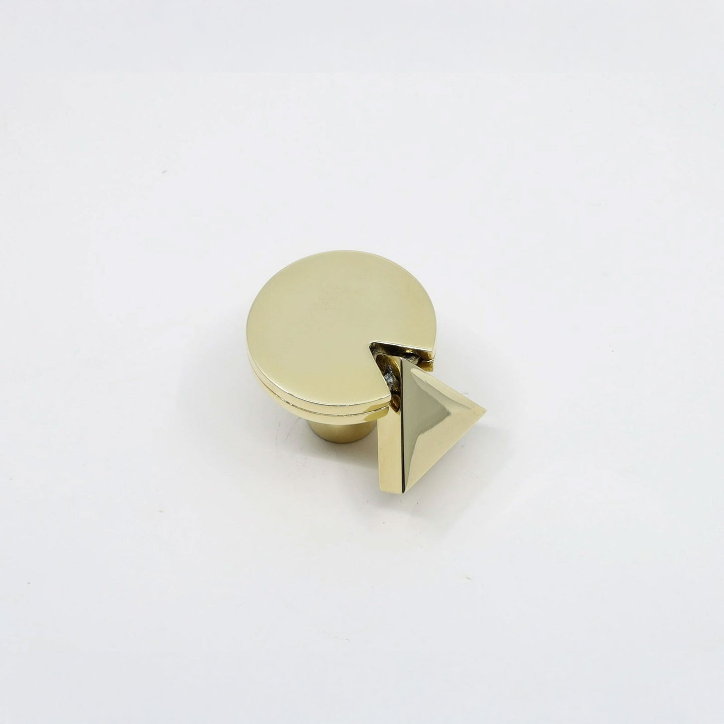 A gold-finished cabinet knob featuring a circular top with a small triangular pyramid accent on the side, shown on a plain white background.