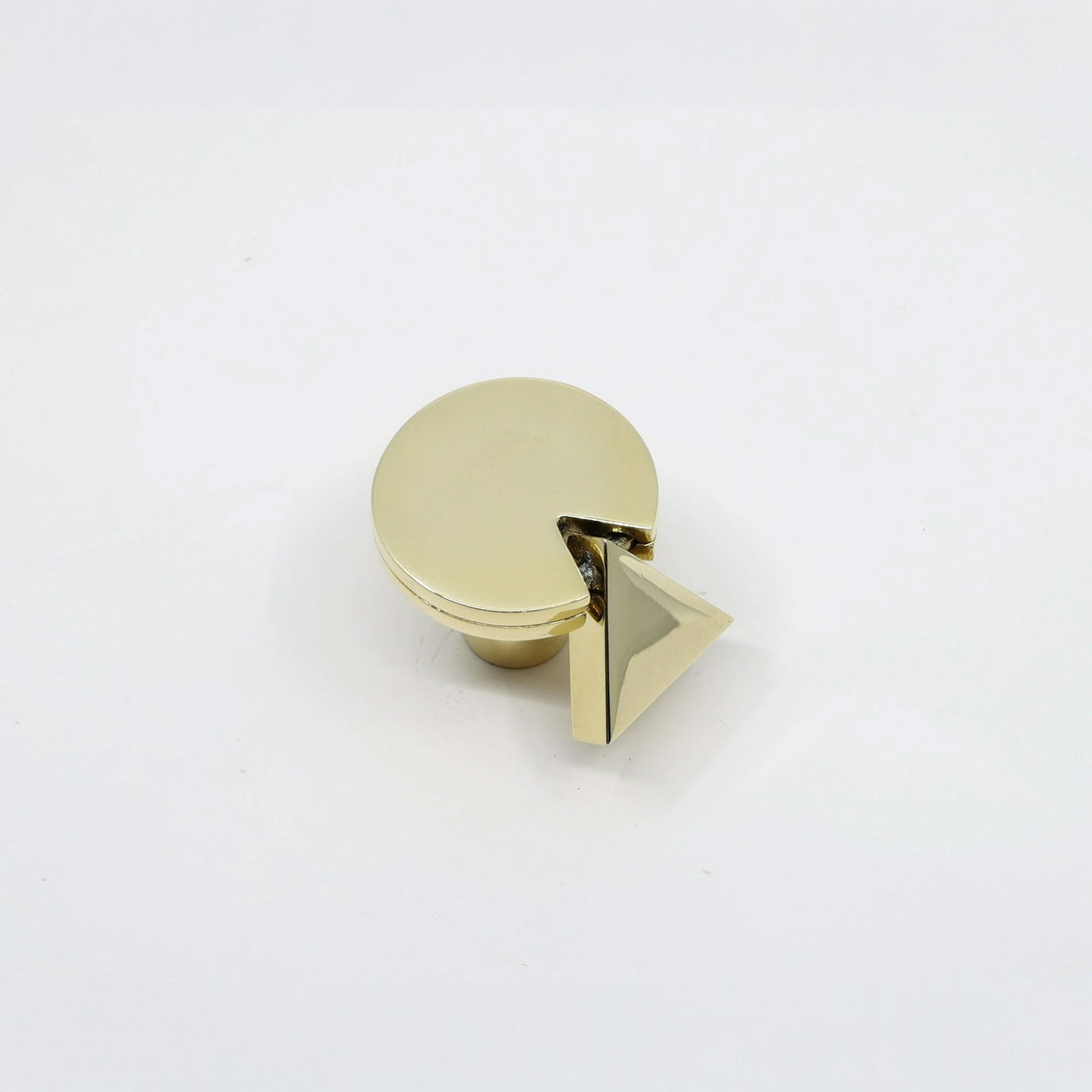 A gold-finished cabinet knob featuring a circular top with a small triangular pyramid accent on the side, shown on a plain white background.