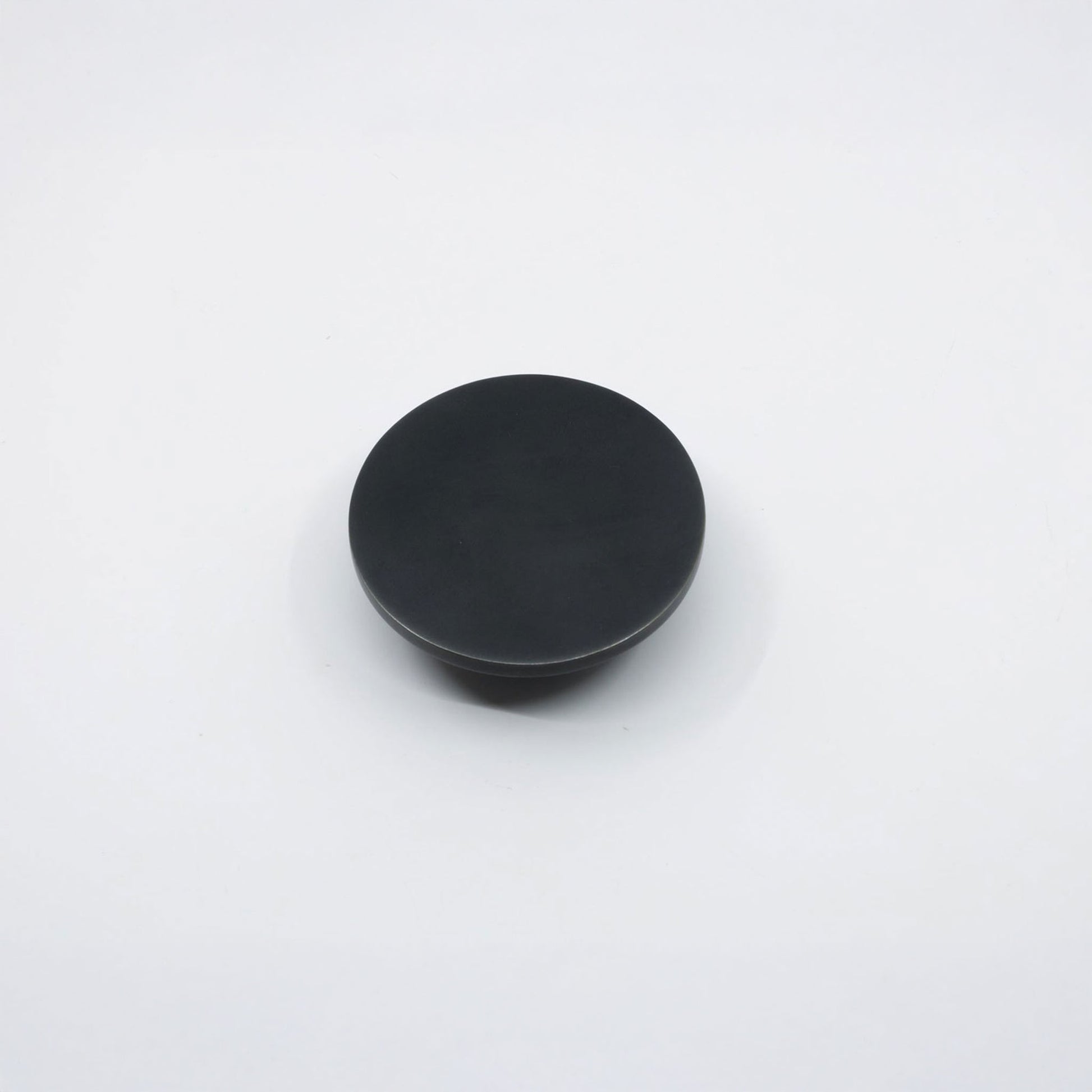 A round, matte black knob shown from a top-down perspective on a clean white background.