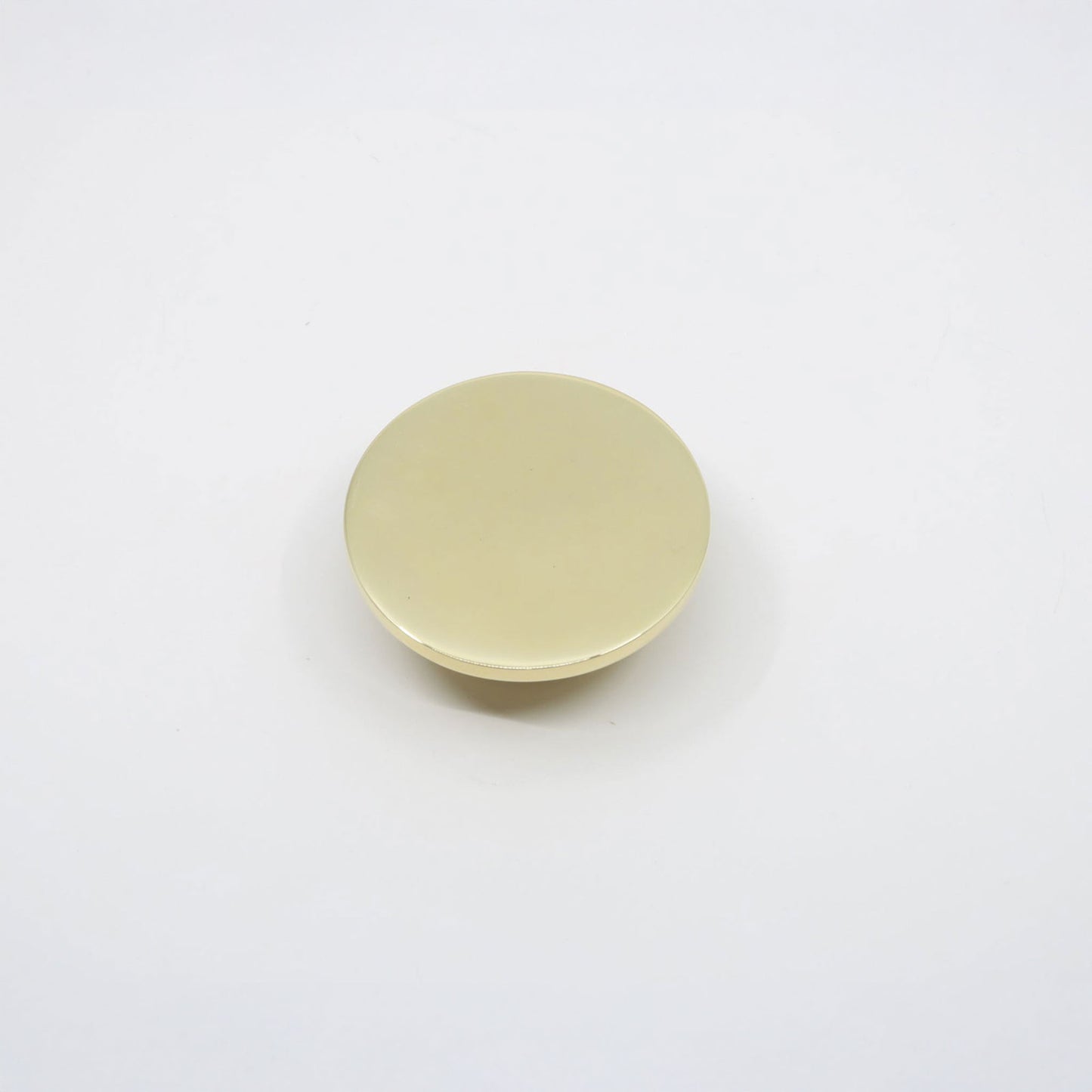 A small, round, flat disc cabinet knob with a smooth, matte pale yellow surface, photographed from directly above on a clean white background.