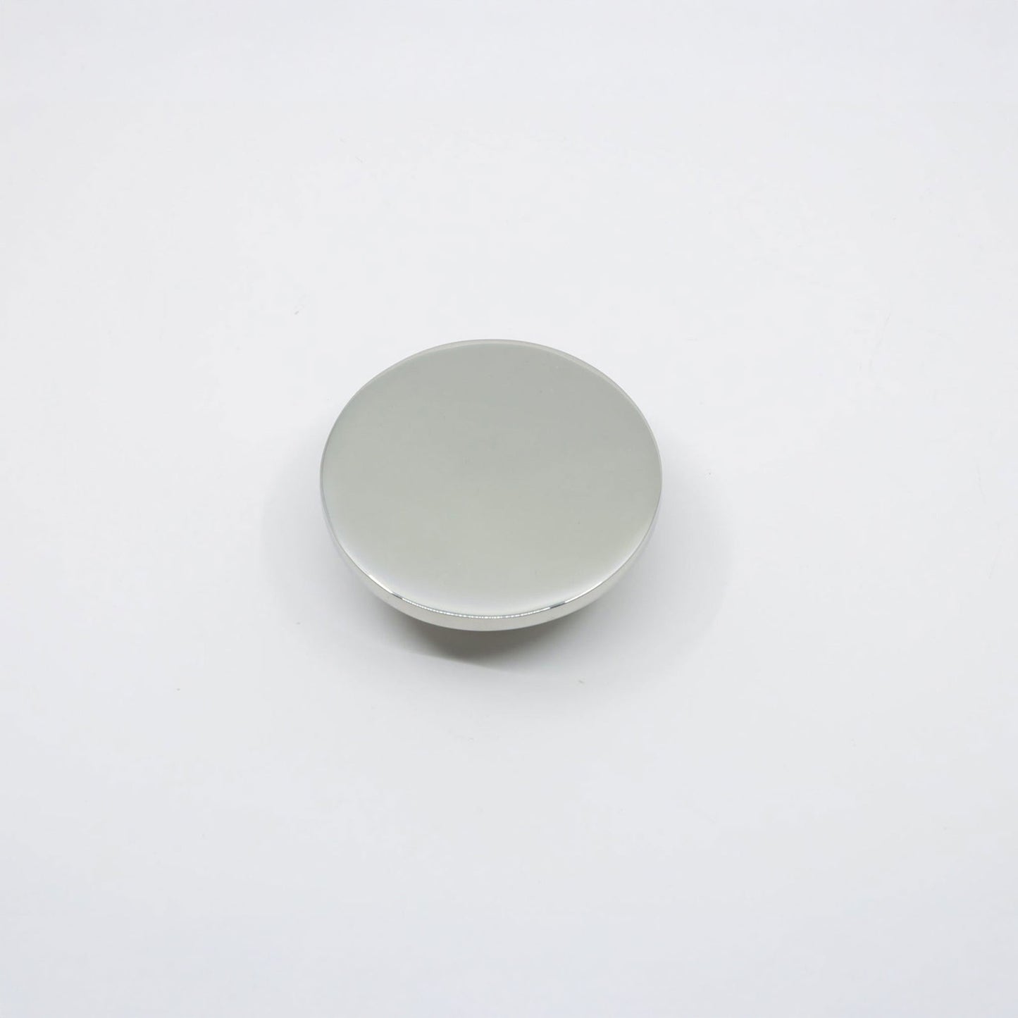 A small, round, flat disc cabinet knob  with a smooth, matte finish, shown closed on a seamless white background.