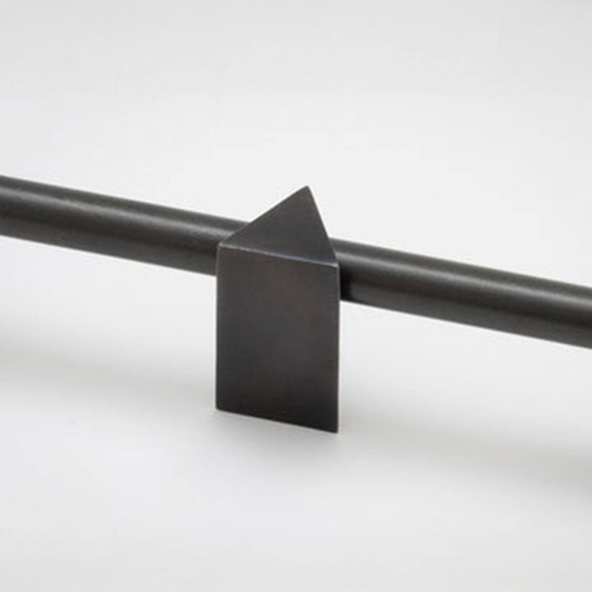 A close-up of a matte black metal cabinet knobs with a geometric triangular finial, shown against a clean light gray background.