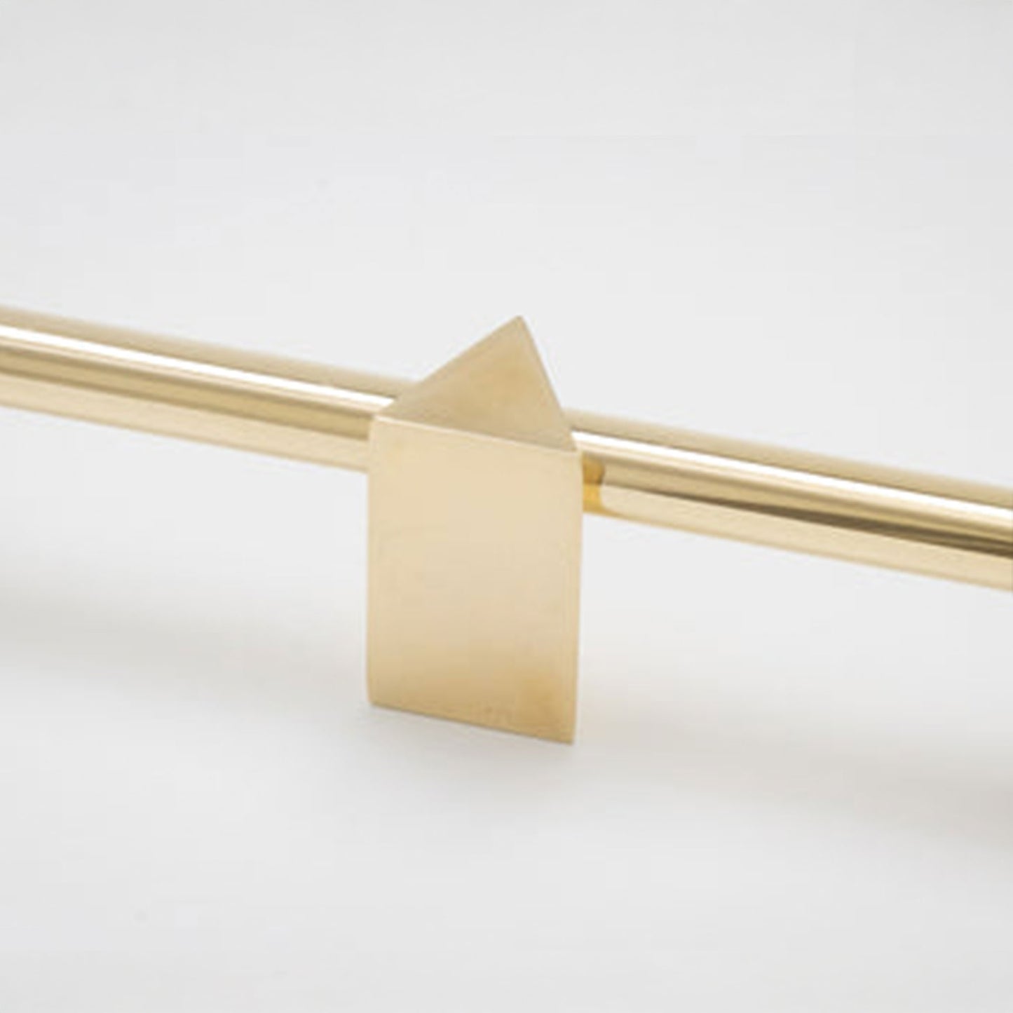 A close-up of a brushed brass or gold metal cabinet knob with a geometric triangular finial, shown against a clean white background.