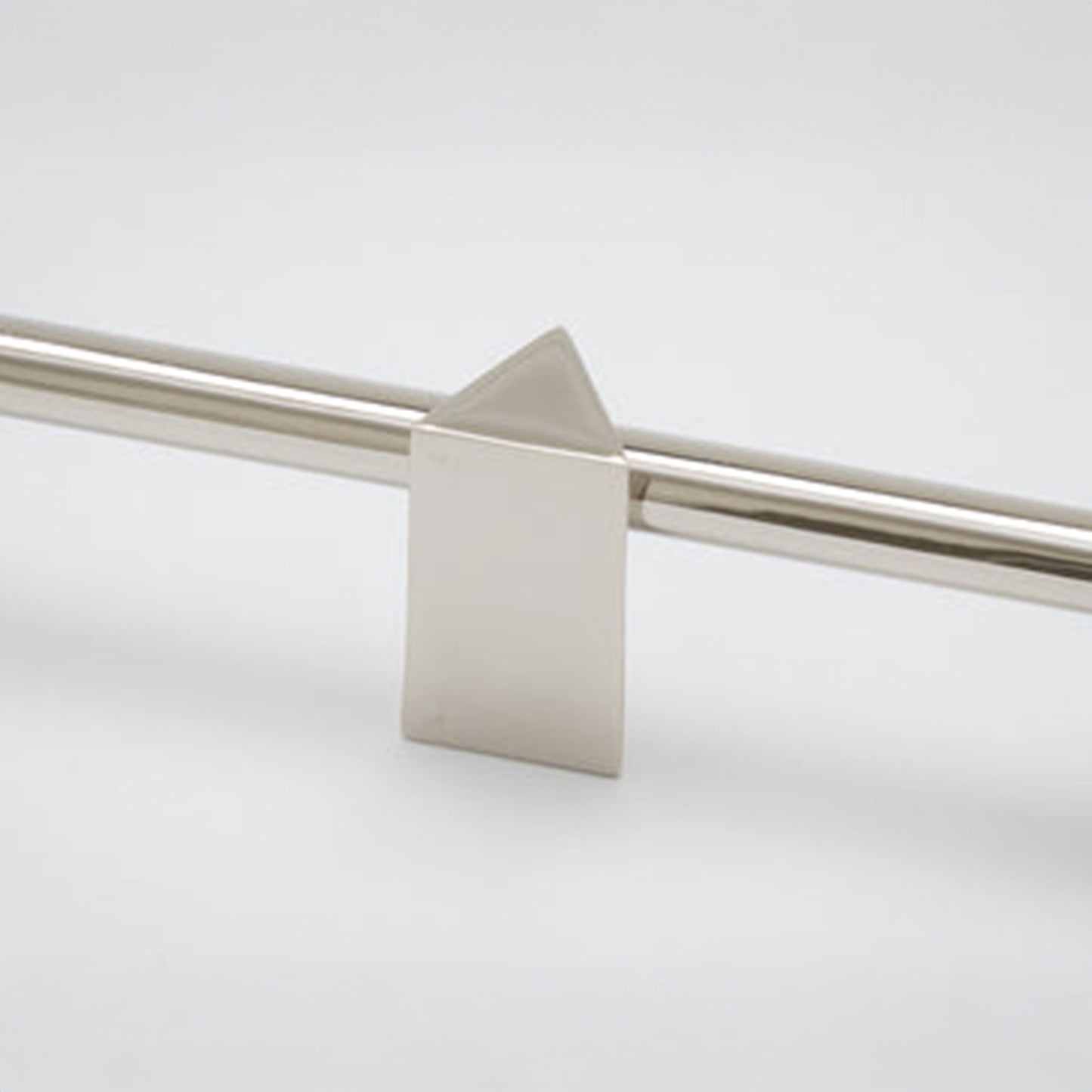 A close-up of a modern metallic cabinet pull featuring a flat rectangular block with a pointed triangular top, mounted on a polished metal bar against a light gray background.