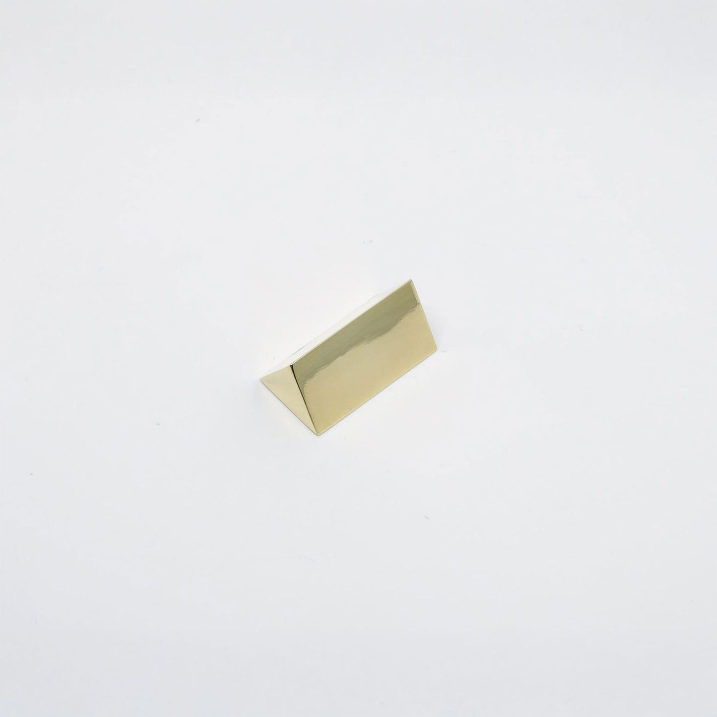 A small polished gold triangular metal r decorative knob, shown on a plain white background.