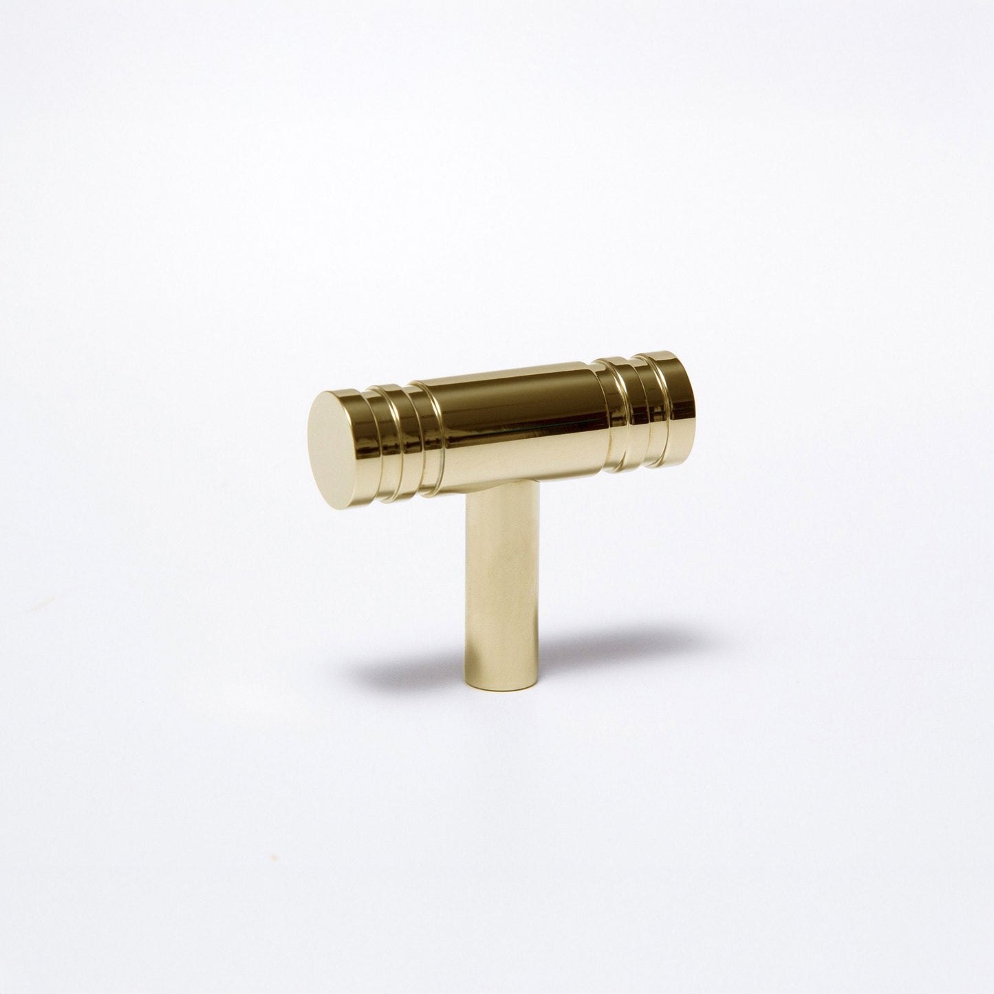 A polished brass T-shaped cabinet pull handle with a cylindrical top and a straight stem, shown on a clean white background.