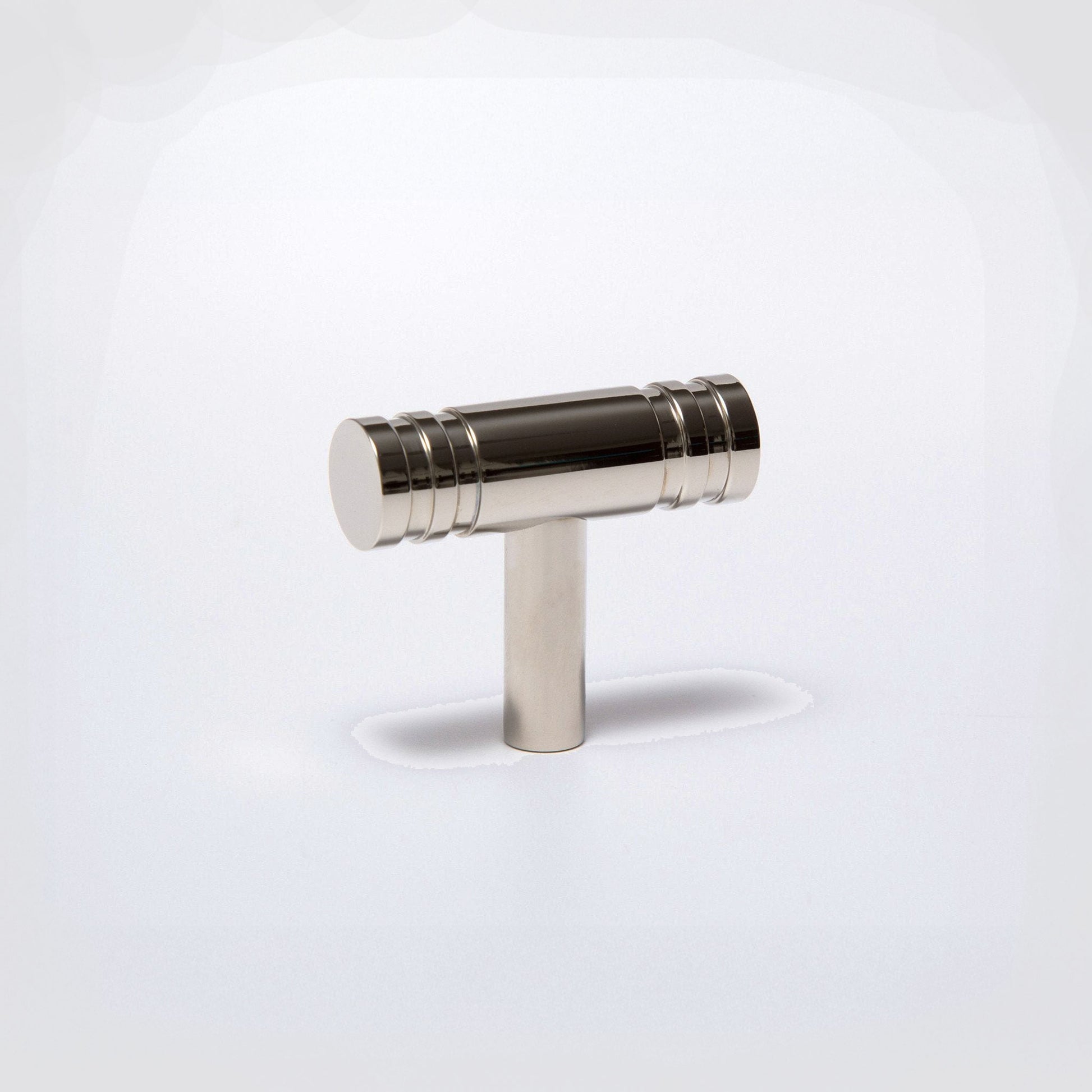 A polished brass T-shaped cabinet knob with a cylindrical handle and a straight post, shown on a clean white background.