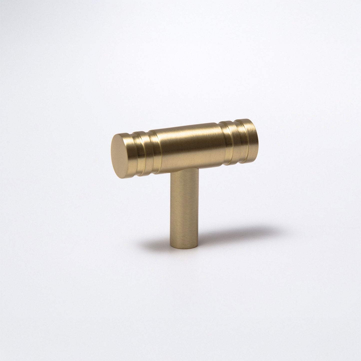 A brass T-shaped cabinet pull handle with a polished metallic finish, shown on a clean white background with a soft shadow.