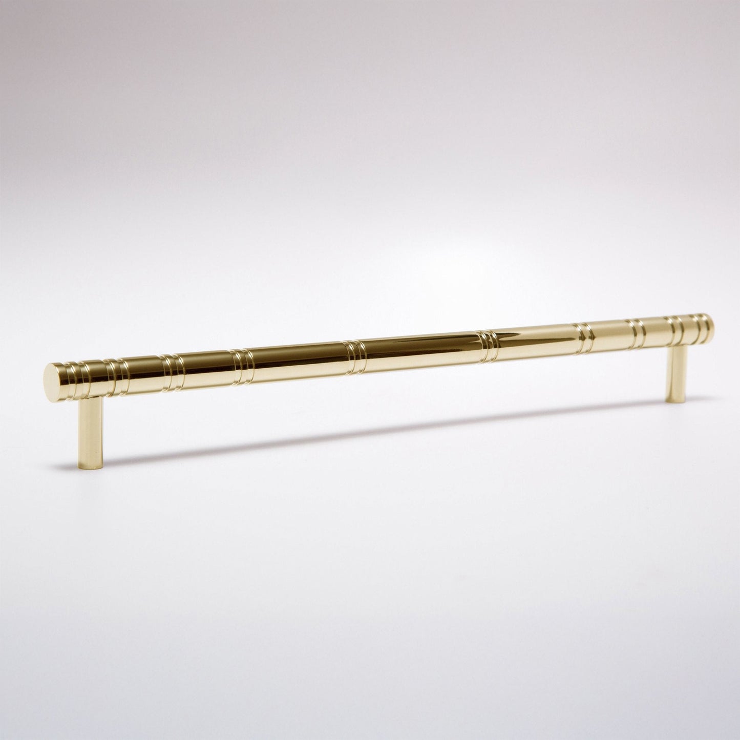 A polished brass cabinet pull handle with a decorative segmented rod design and cylindrical end caps, shown on a clean white background.