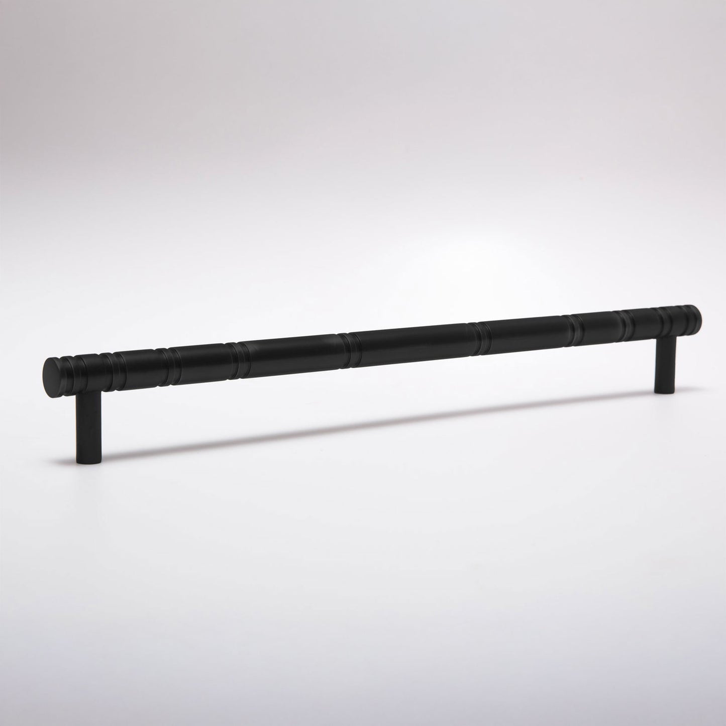 A long black metal cabinet pull handle with a textured, segmented grip and two short mounting posts, shown on a light gray studio background.