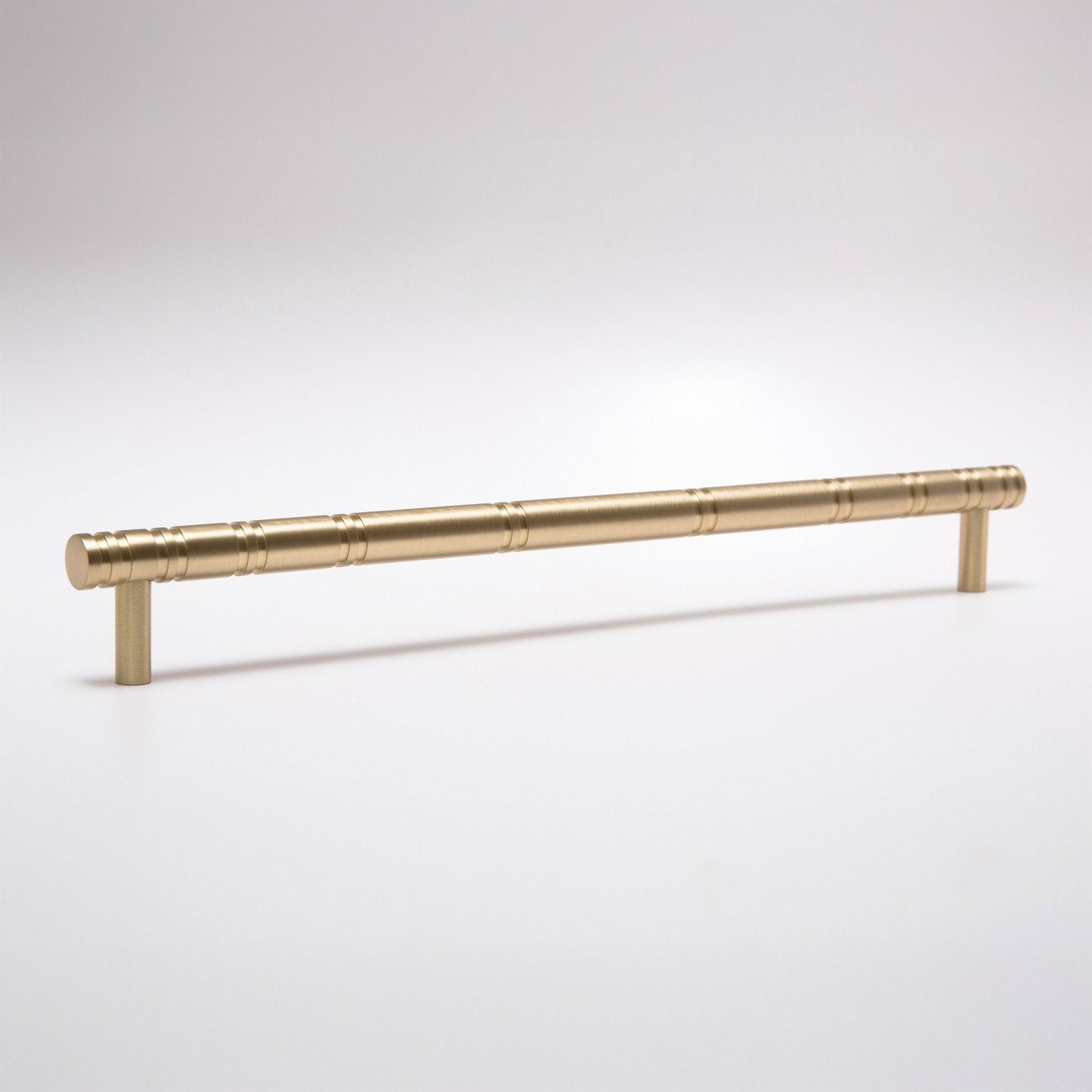 A brushed brass cabinet pull handle with a cylindrical rod and two short posts, shown on a clean light gray background.