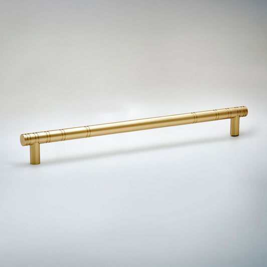 A modern cylindrical cabinet pull handle in a brushed gold finish, featuring a subtle textured pattern near the ends and mounting posts, shown on a neutral light gray background.