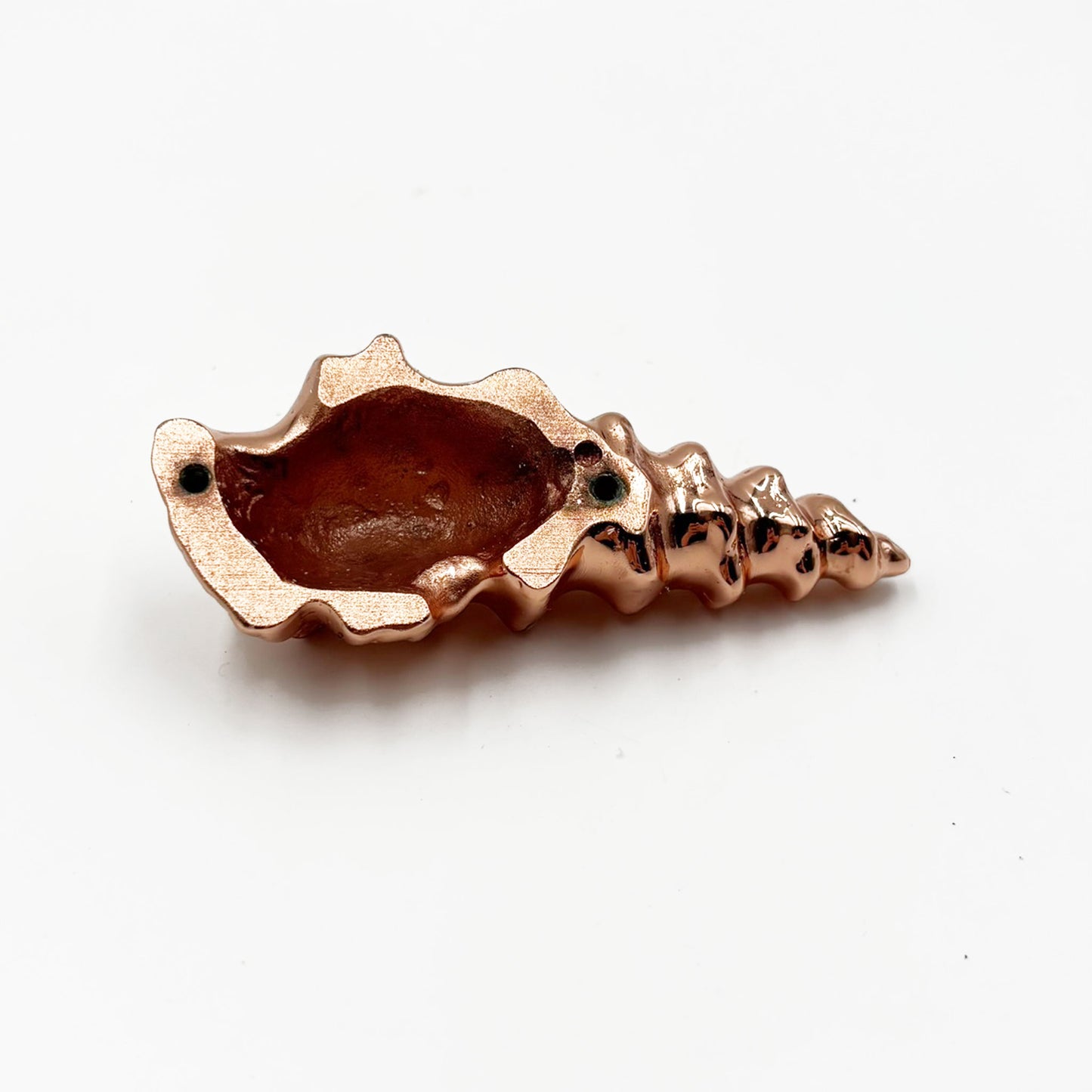 The reverse side of a small metallic shell-shaped cabinet pull in a shiny copper finish, photographed on a plain white background.