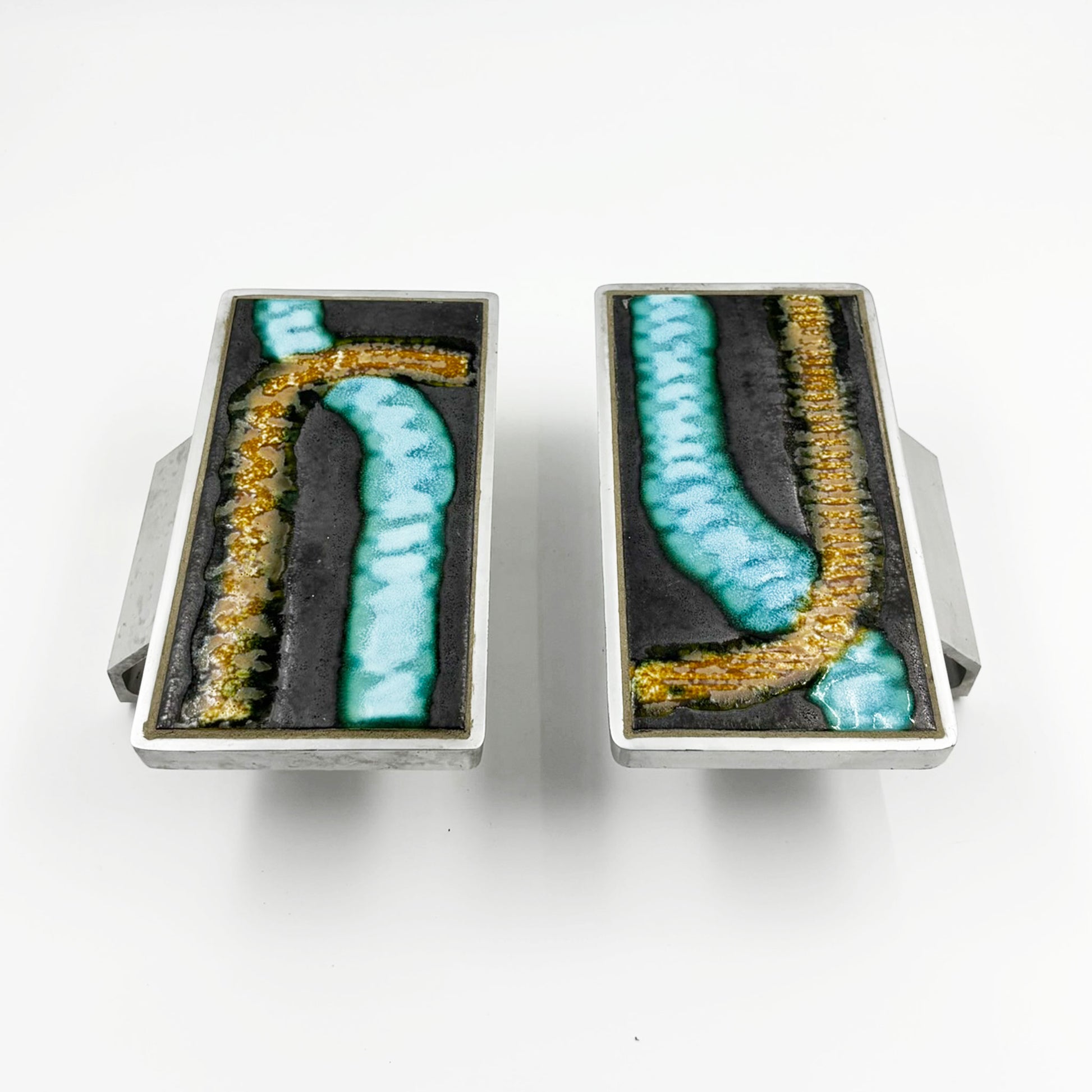 A pair of rectangular silver-toned door handles with abstract turquoise and gold textured inlay on a dark background, shown against a plain white background.