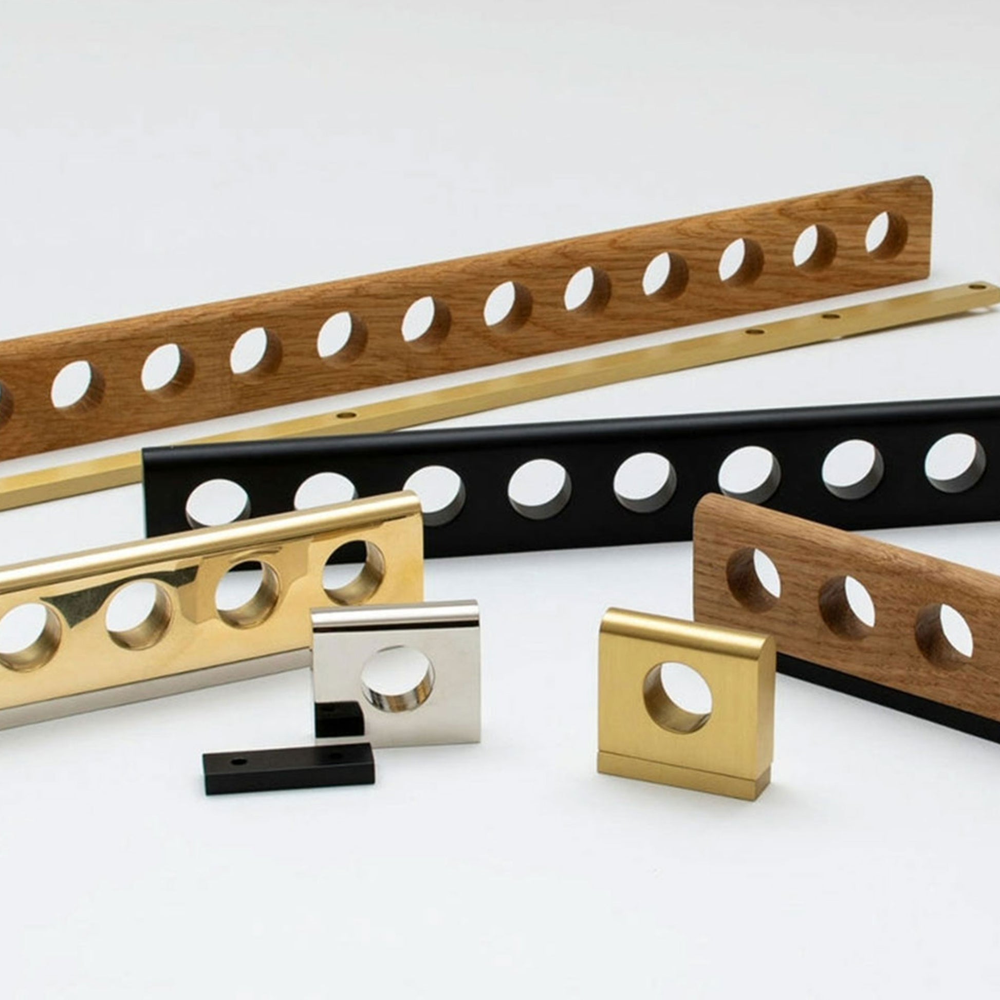 A set of metal and wood cabinet pulls with circular cutouts, shown in gold, black, silver, and natural wood finishes on a clean white background.