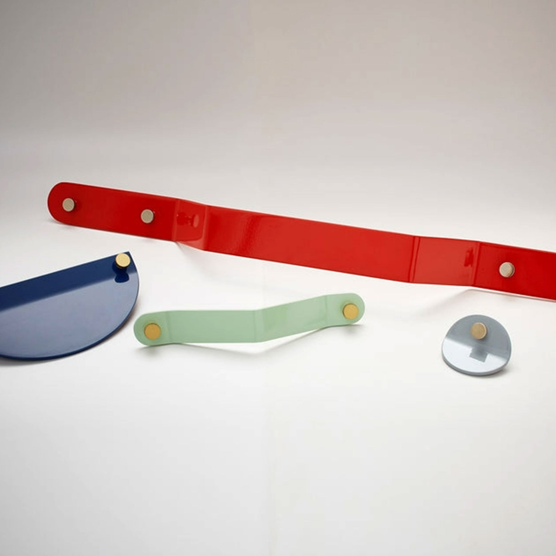 Four colorful metal cabinet pulls in red, blue, mint green, and silver, arranged on a clean white background.
