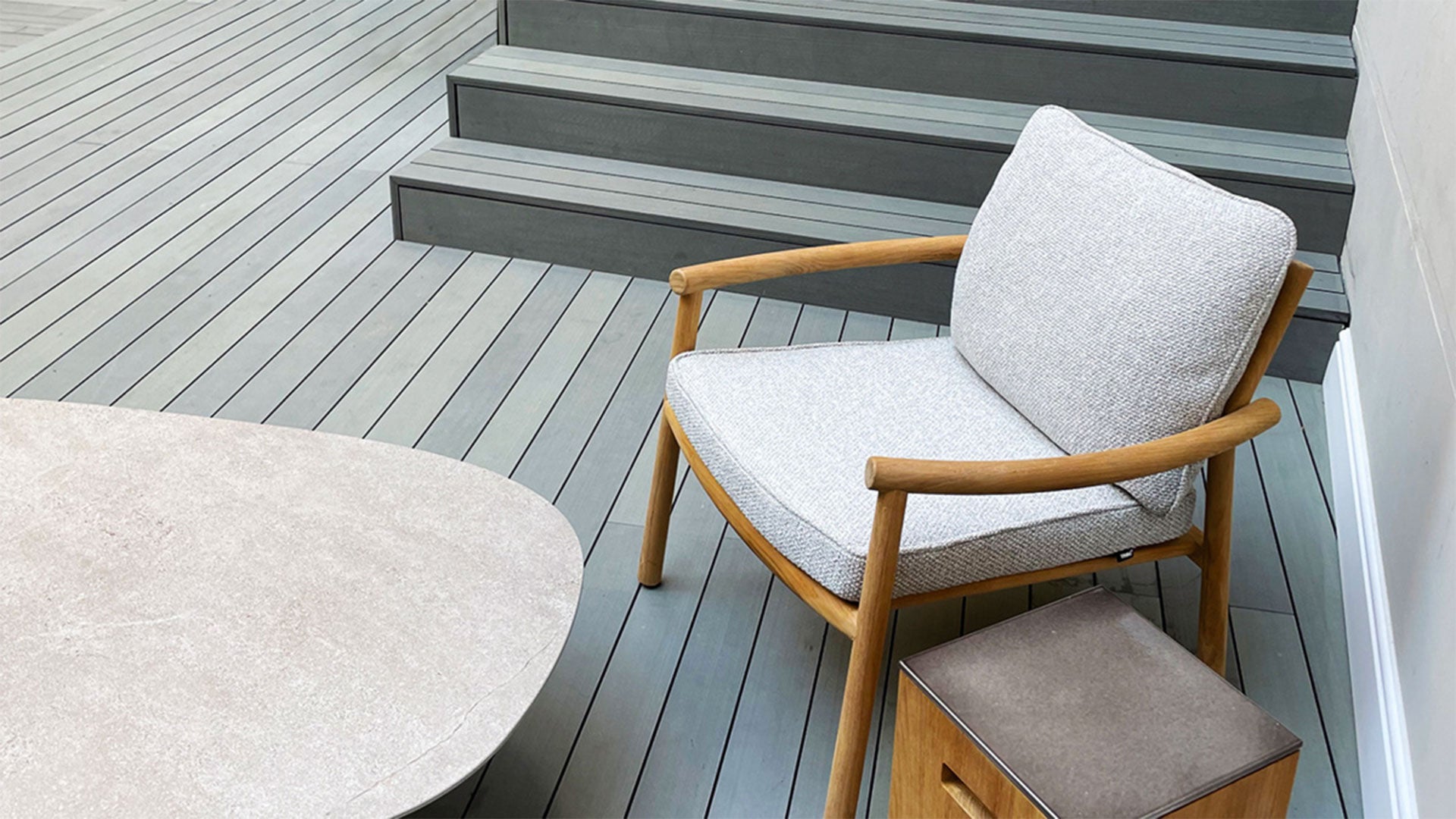 a short run starway covered with Esthec decking and a modern outdoor chair and side table sitting atop it