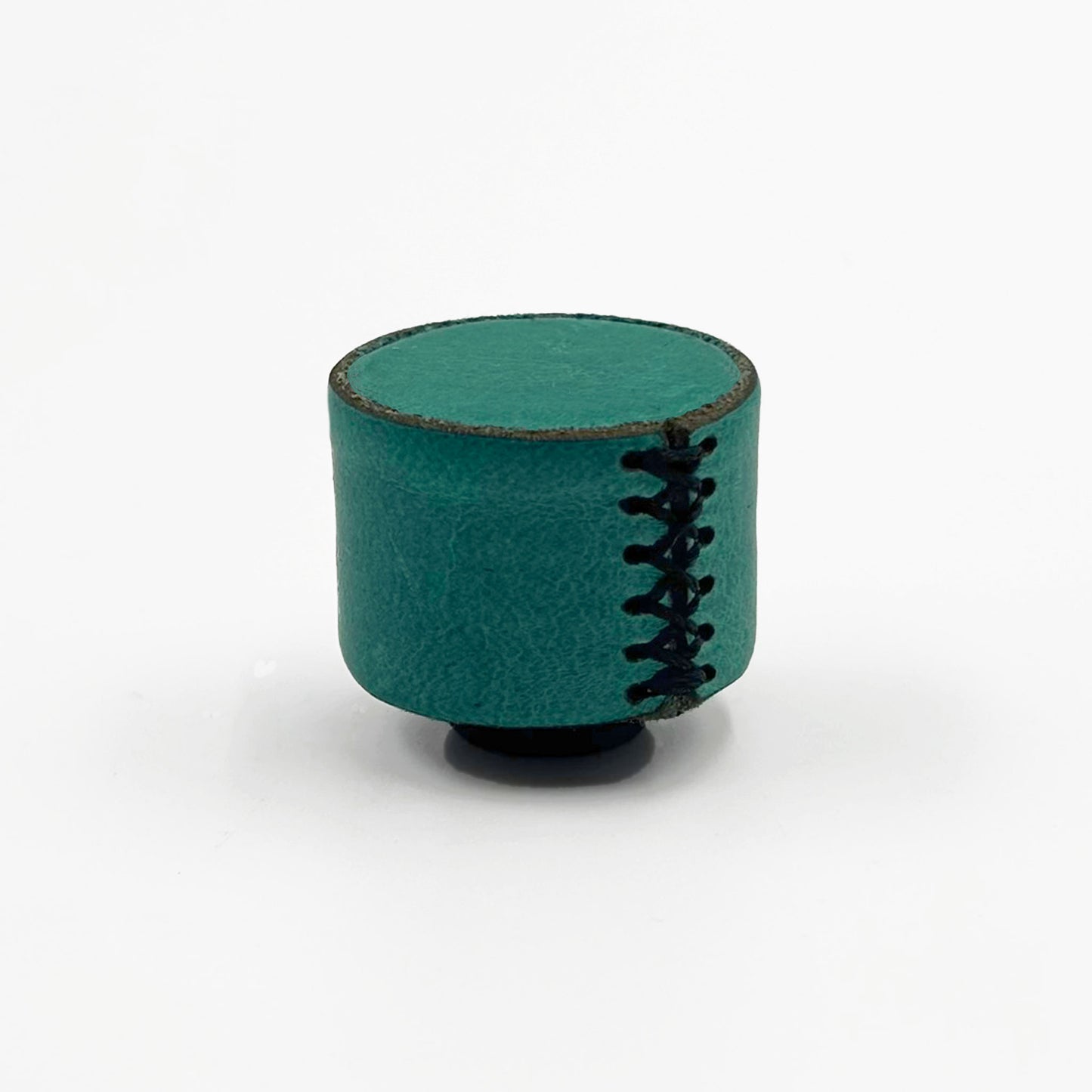 A small cylindrical teal leather cabinet knob with texture and black decorative stitching, standing on a black circular base against a plain white background.