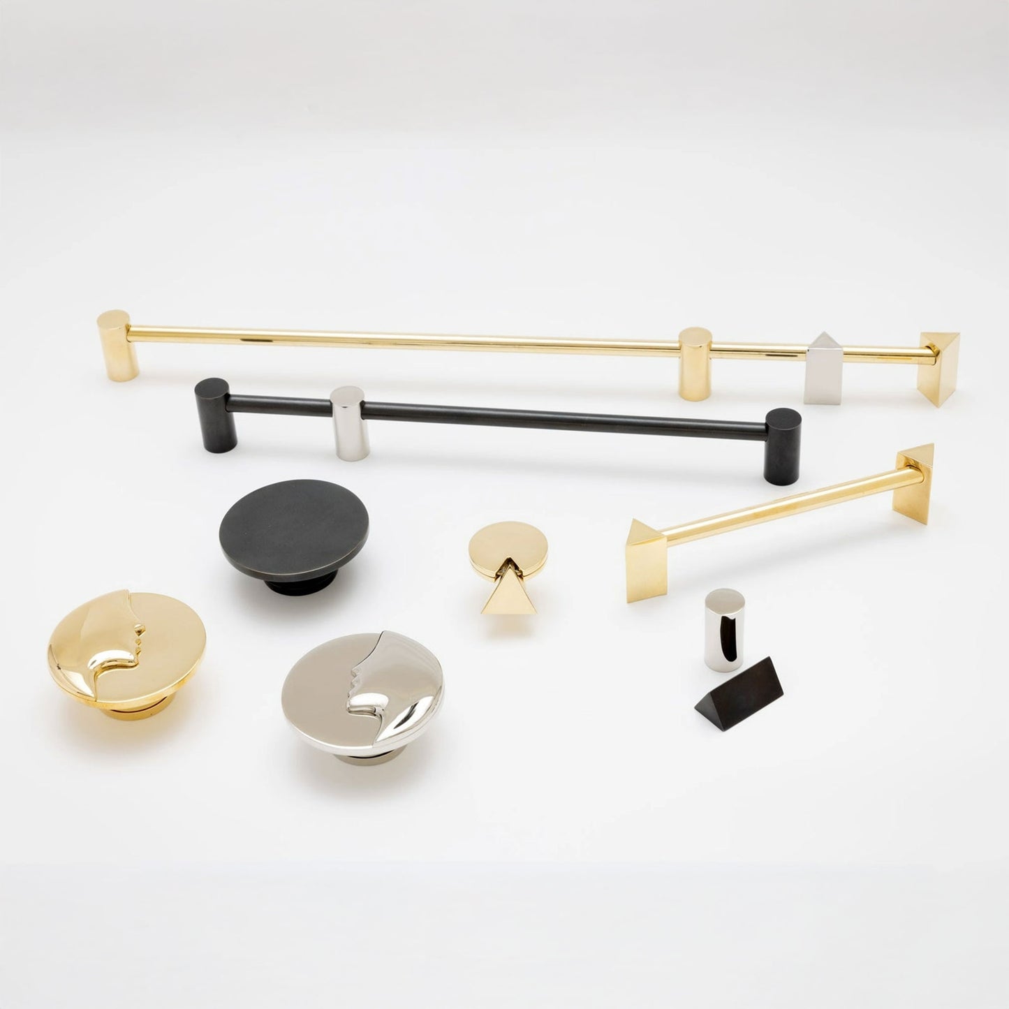 A collection of modern cabinet hardware and drawer pulls displayed on a clean white background, including two towel bars and several round and geometric knobs in polished gold, matte black, and brushed silver.