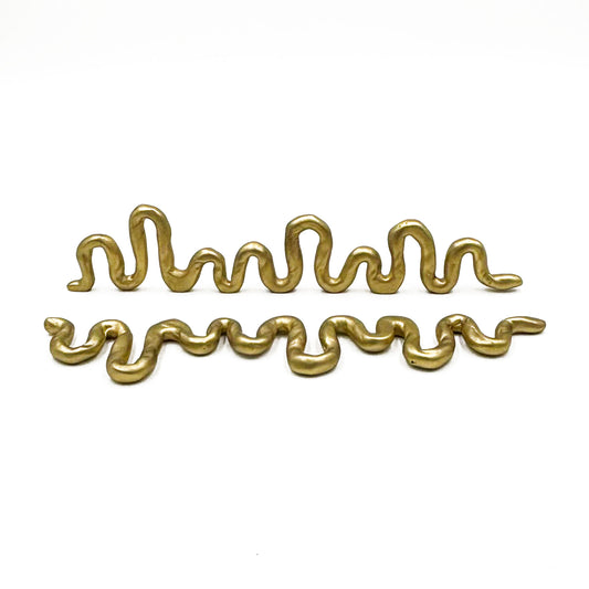 Two wavy, snake-like metallic gold cabinet pulls displayed horizontally on a clean white background.