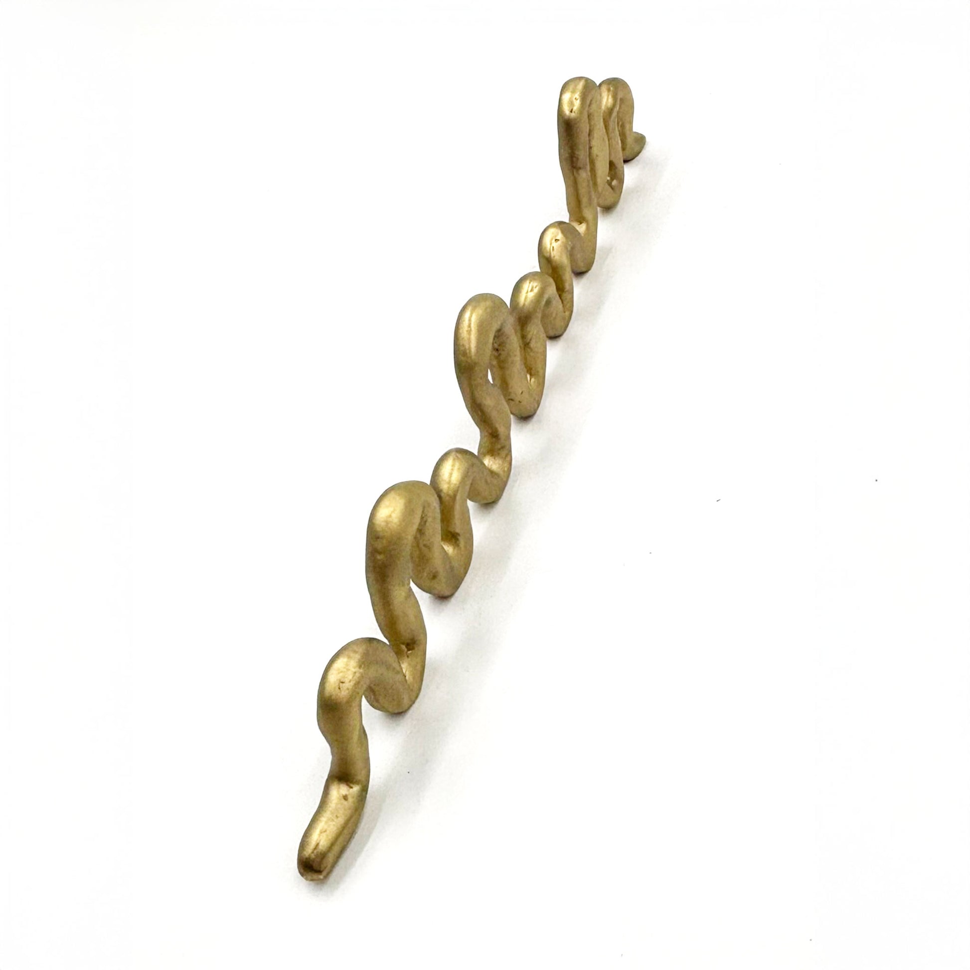 A squiggly snake shaped matte brass colored cabinet pull shown from the top on a white background