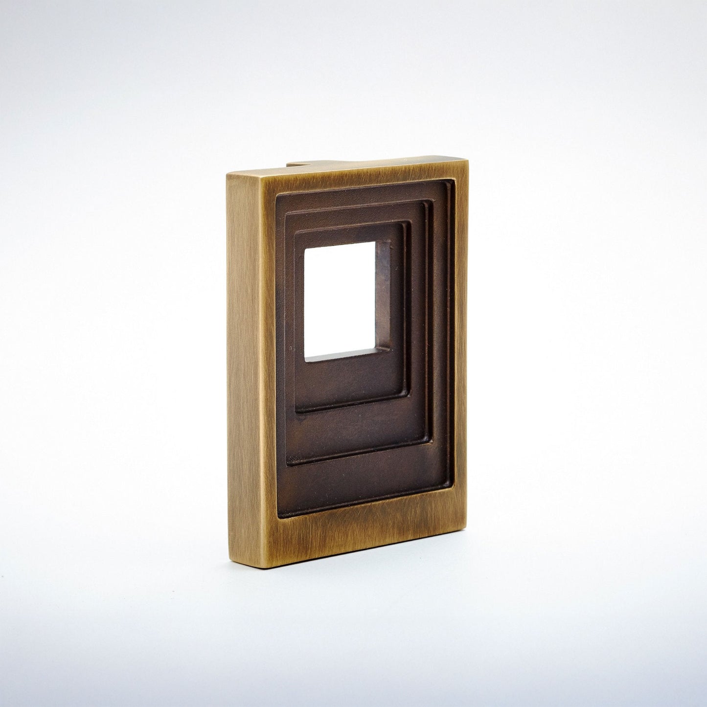 A rectangular metal cabinet pull with a warm brass/gold outer border and a dark brown recessed center, shown on a clean white studio background.