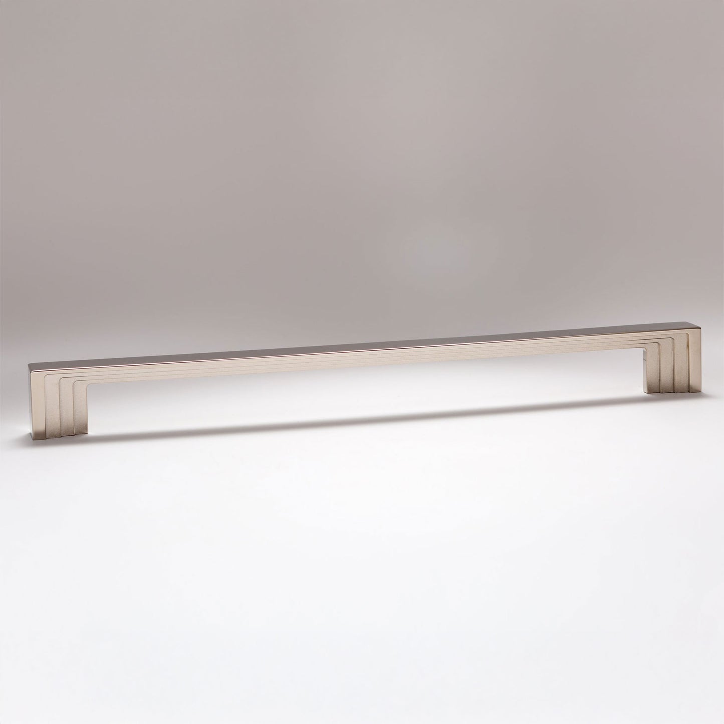 A long, rectangular cabinet pull handle with a brushed metallic finish, shown horizontally against a neutral gray background.