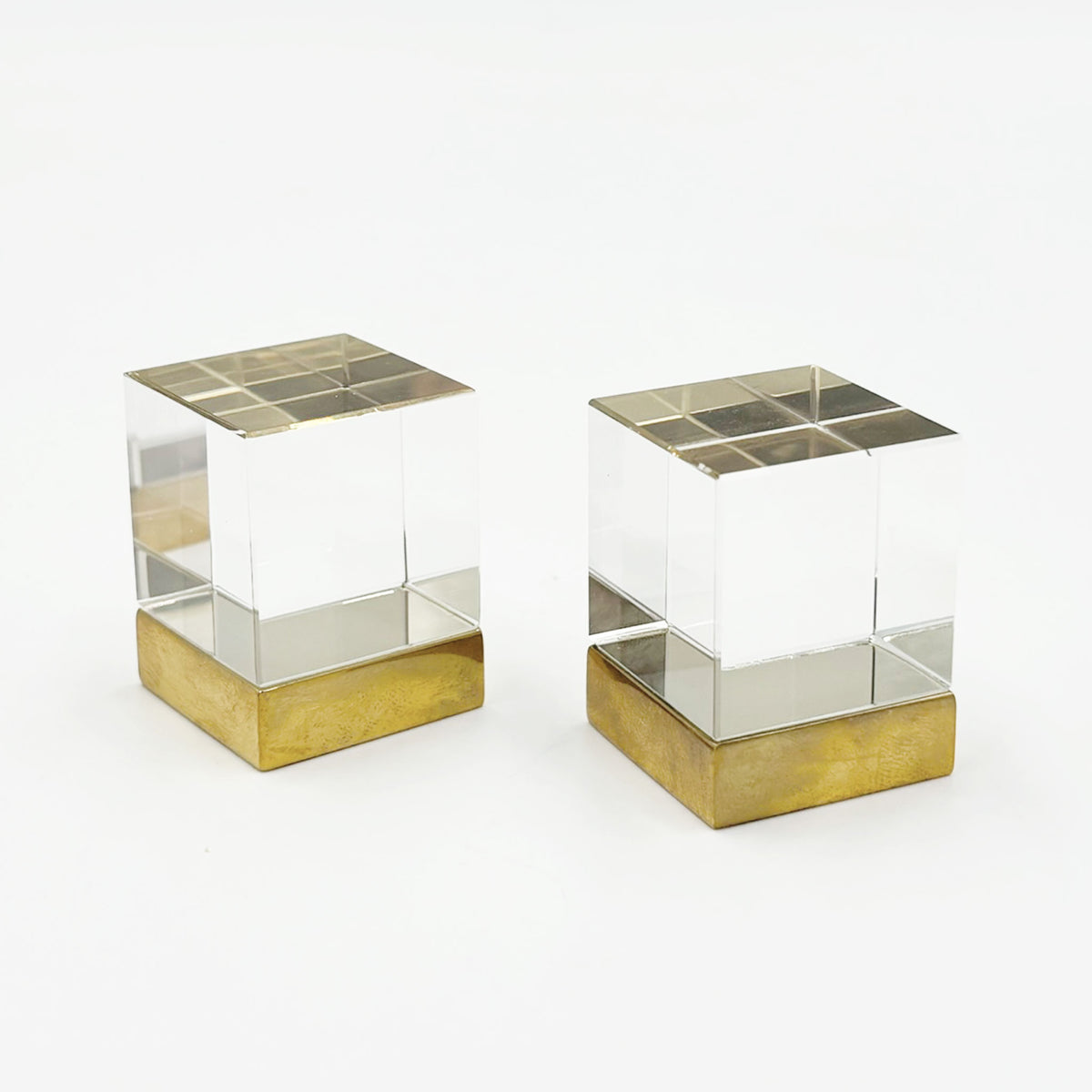 Two Glass cube shaped cainet knobs with unlacquered brass bases on a white background