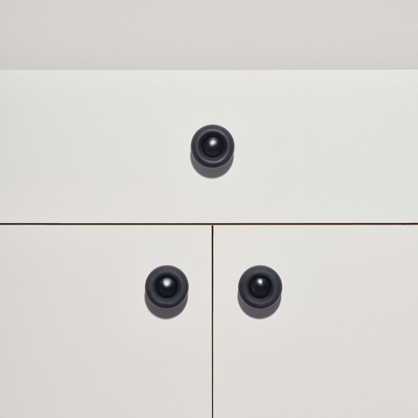 White cabinet with black colored cabinet knobs on a white background