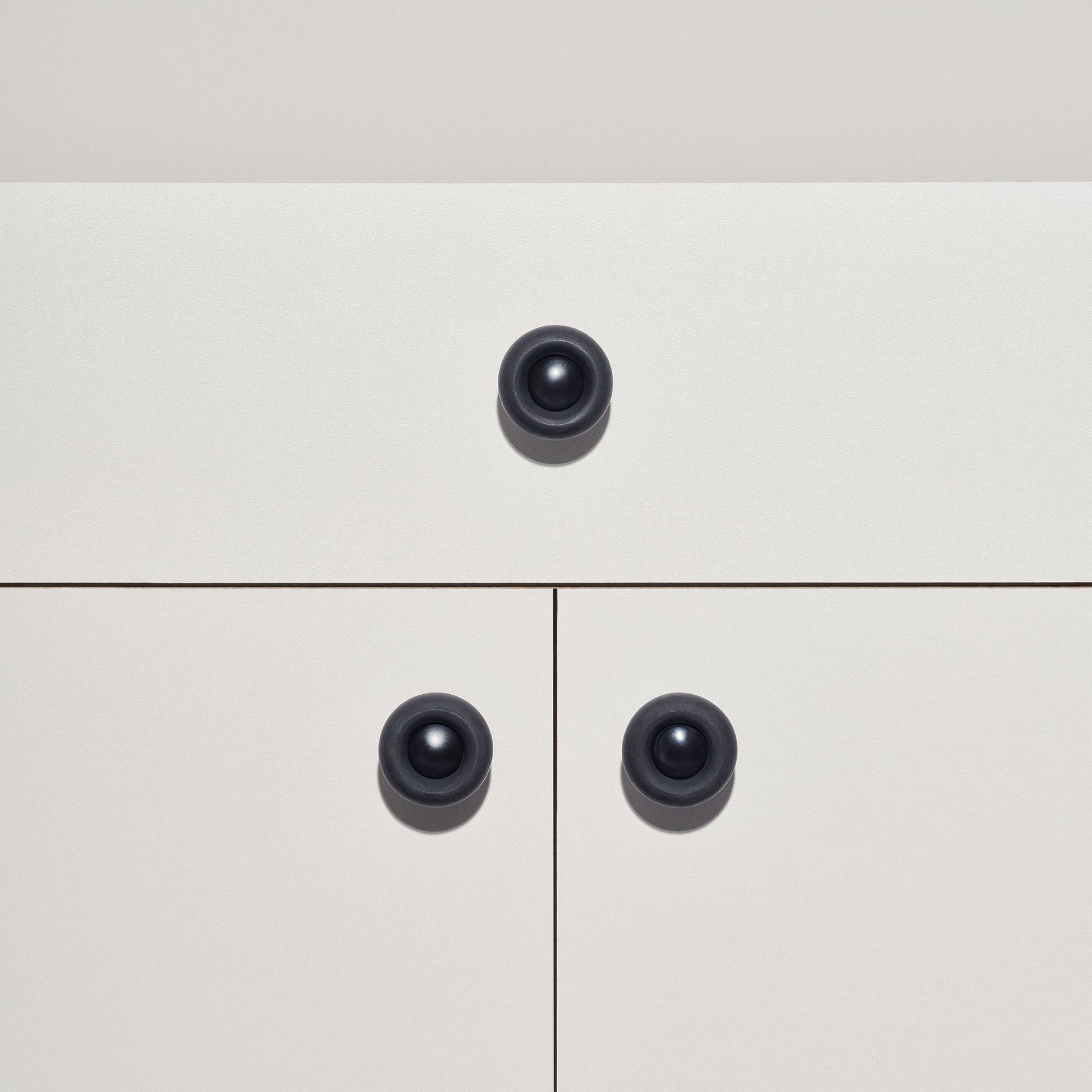 White cabinet with black colored cabinet knobs on a white background
