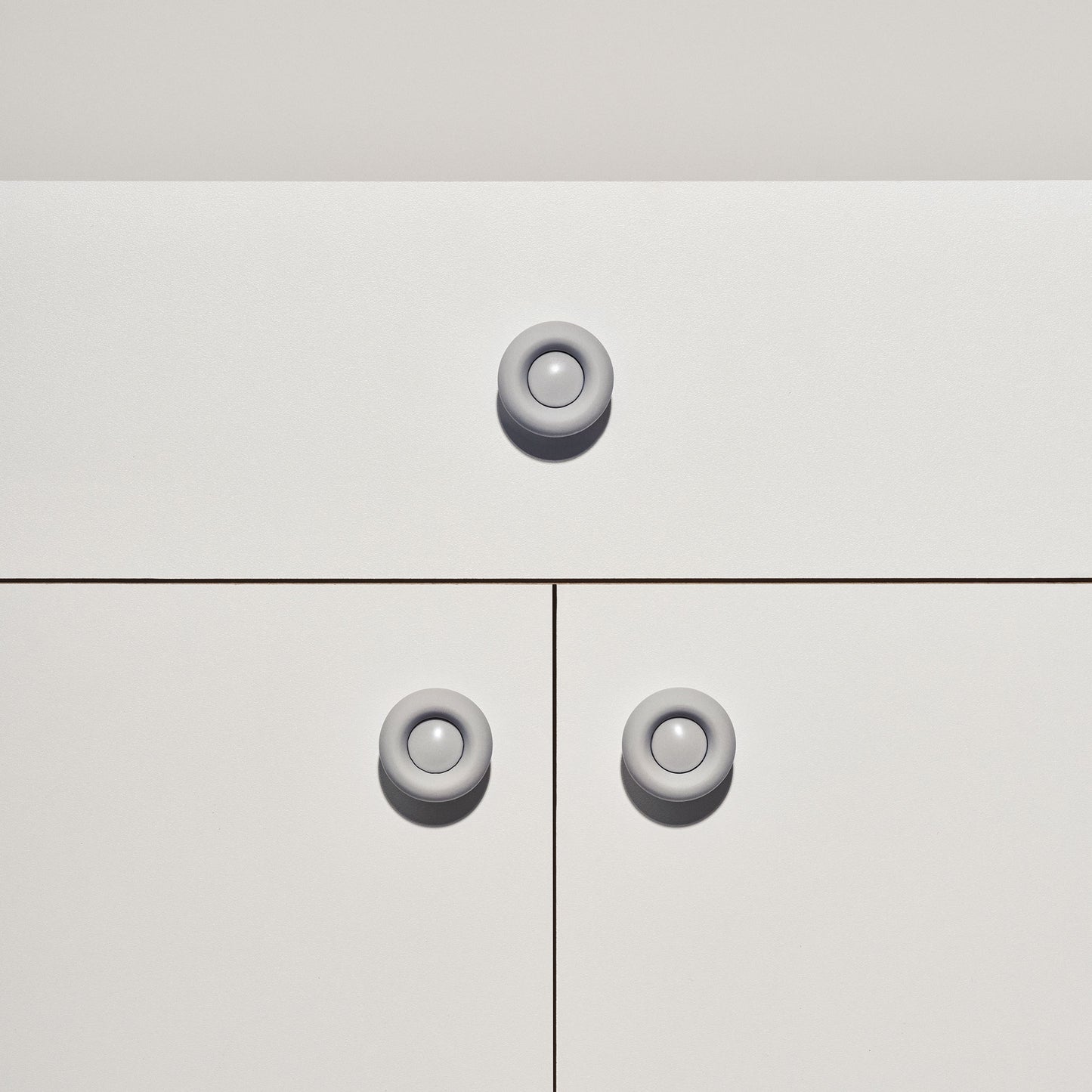 White cabinet with pale grey colored cabinet knobs on a white background