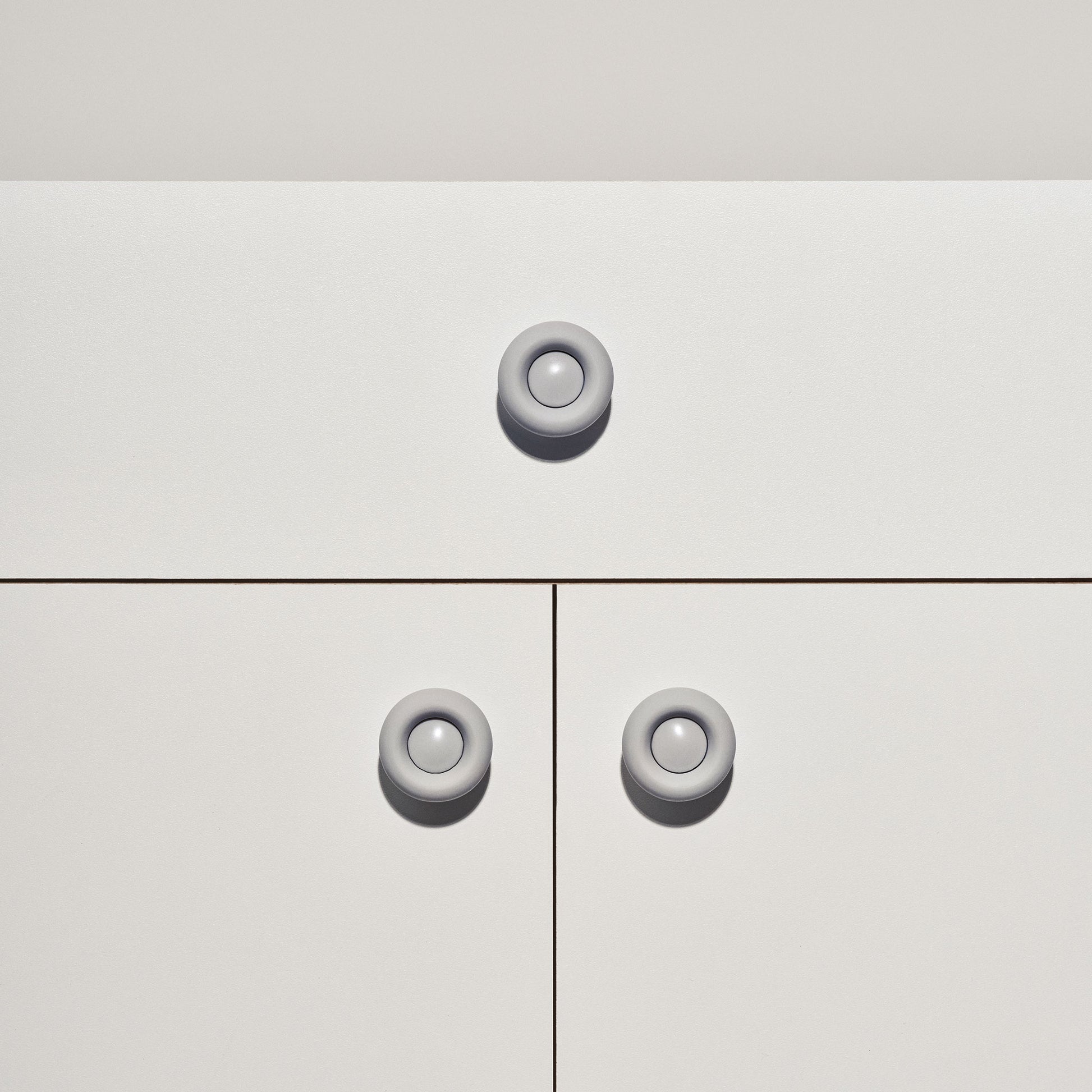 White cabinet with pale grey colored cabinet knobs on a white background